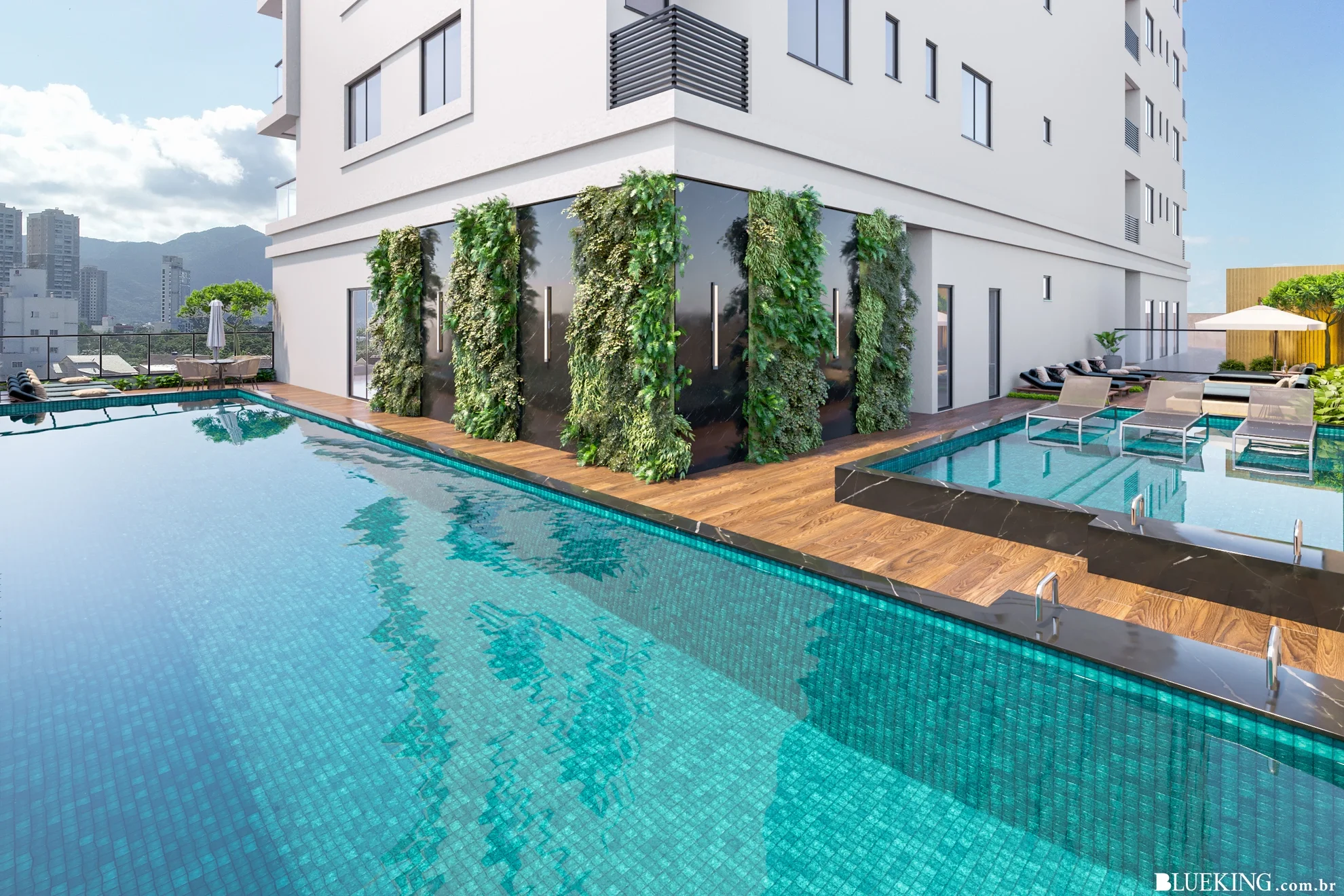 Piscina de um prédio moderno com deck de madeira, espreguiçadeiras e área com sombra, ao fundo cidade com prédios e montanhas ao longe.