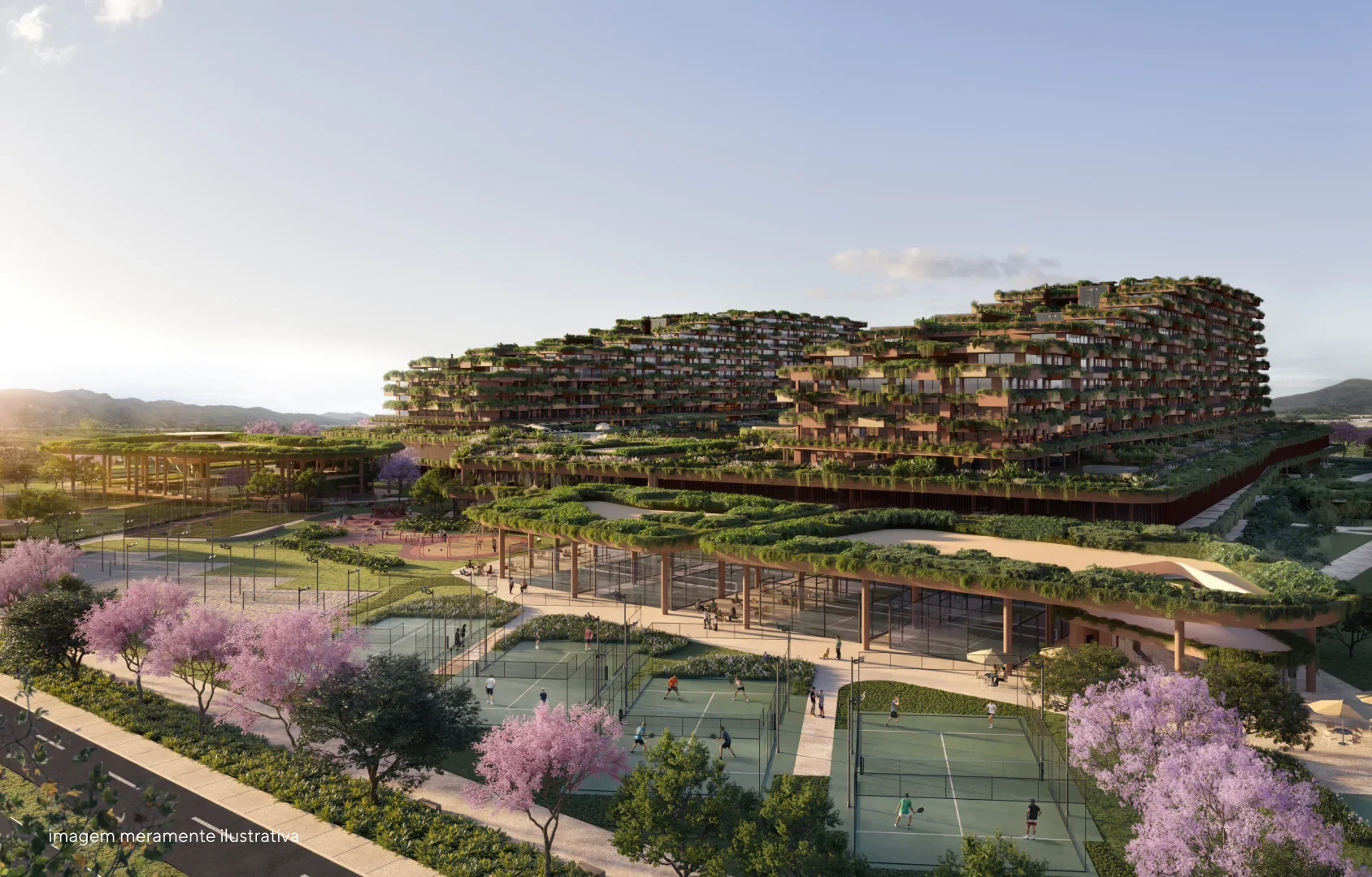 Vista de um complexo de edifícios modernos com áreas verdes e quadras de tênis, rodeado por árvores de flores rosas, sob céu claro com sol nascente ou poente.