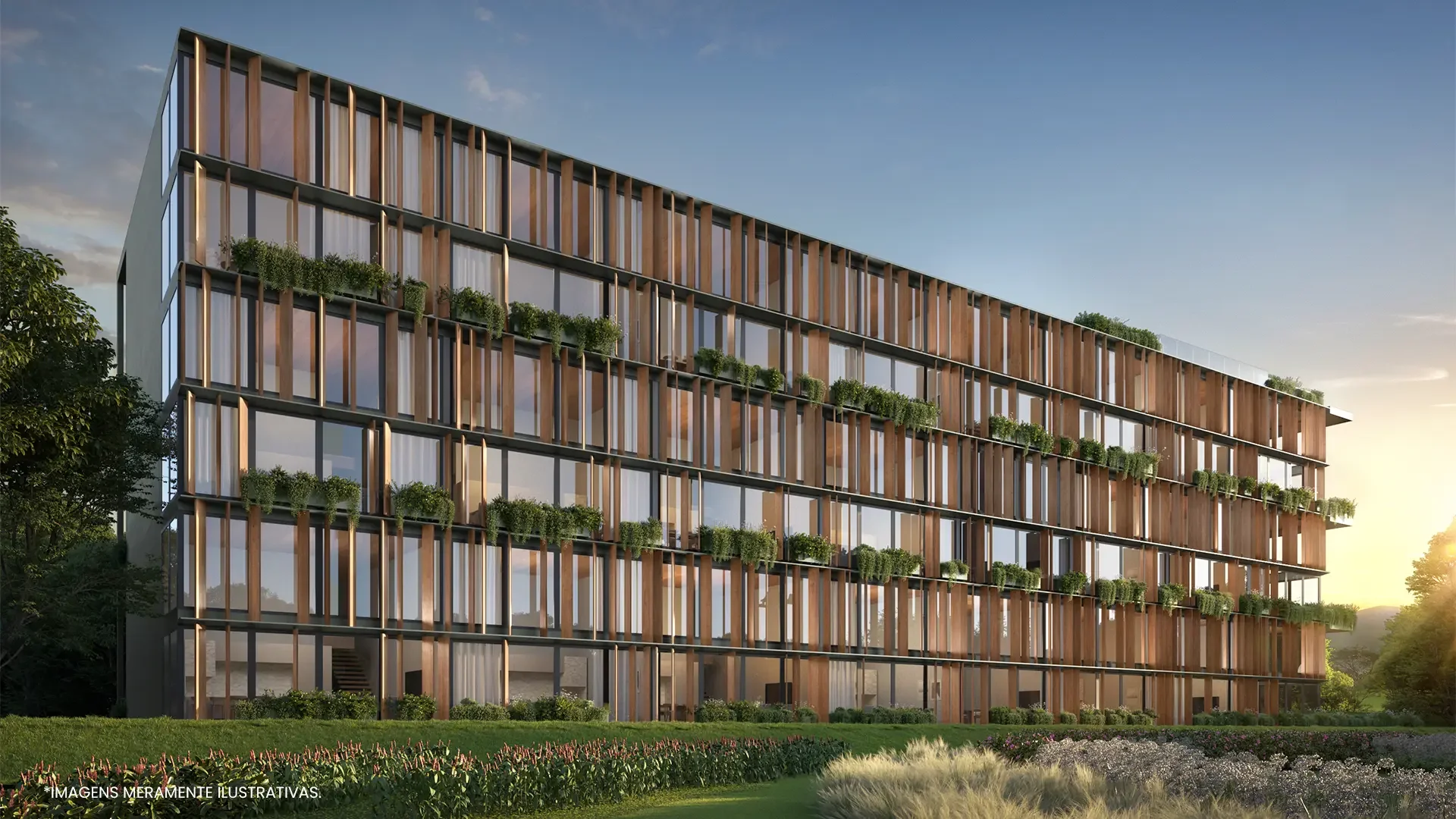 Edifício moderno com fachada de vidro e painéis de madeira, várias janelas e plantas decorativas em varandas, cercado por vegetação e flores, ao pôr do sol.