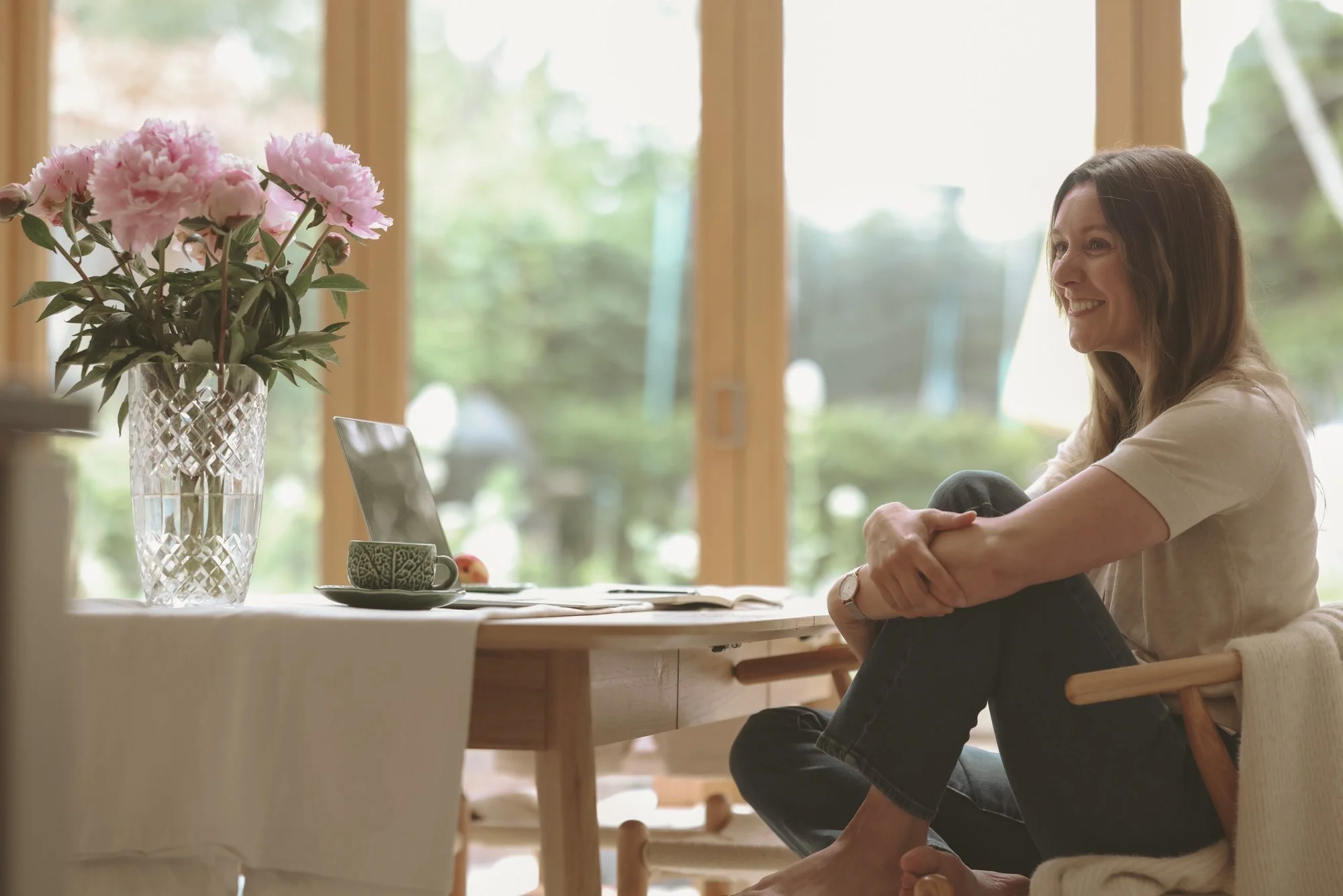 A picture of Becky Lacey, the founder of Joyfully Honest sitting at a table relaxed and smiling.
