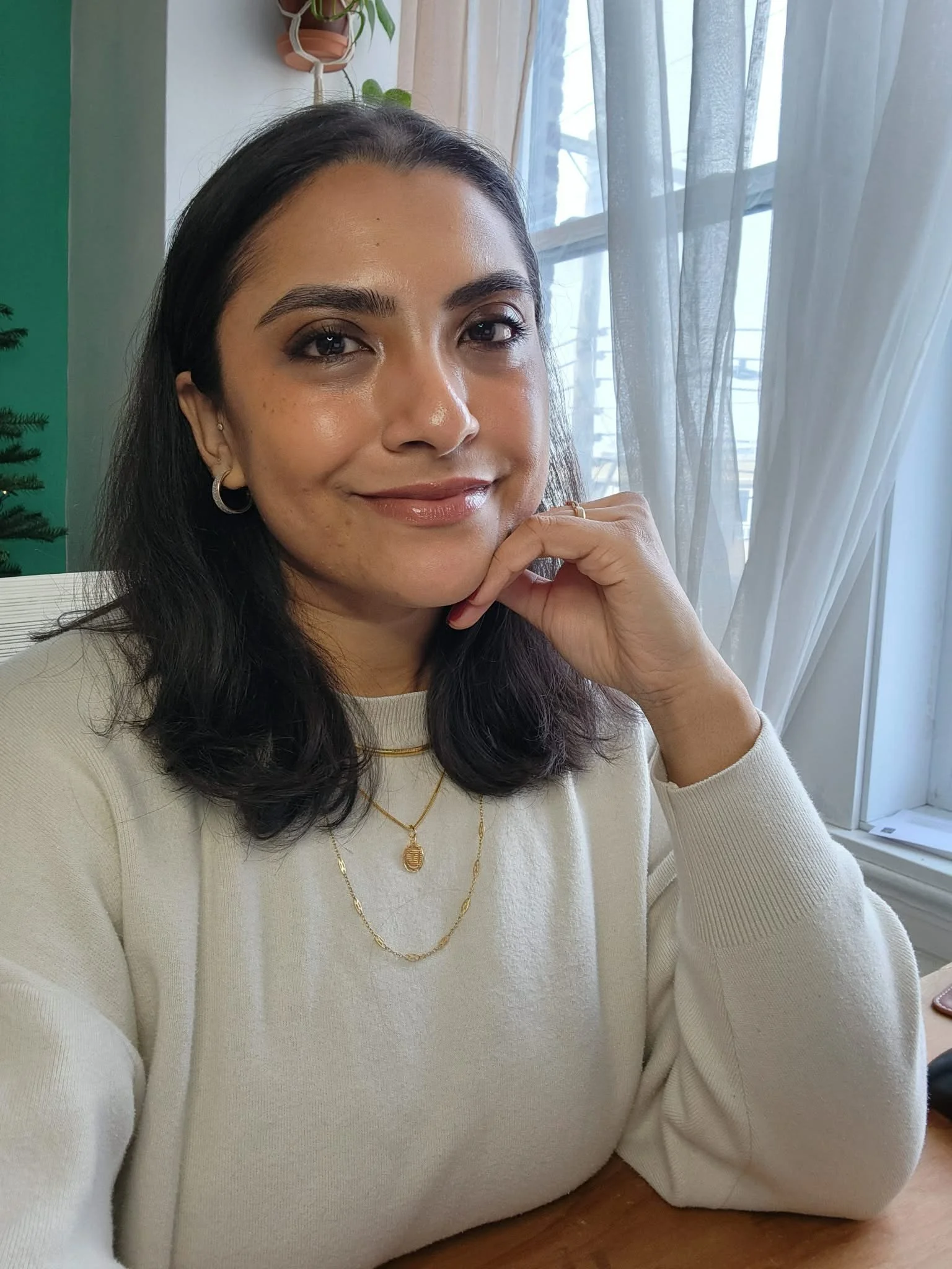 Taharima Habib sitting at her desk, smiling at the camera with her hand tucked under her chin.