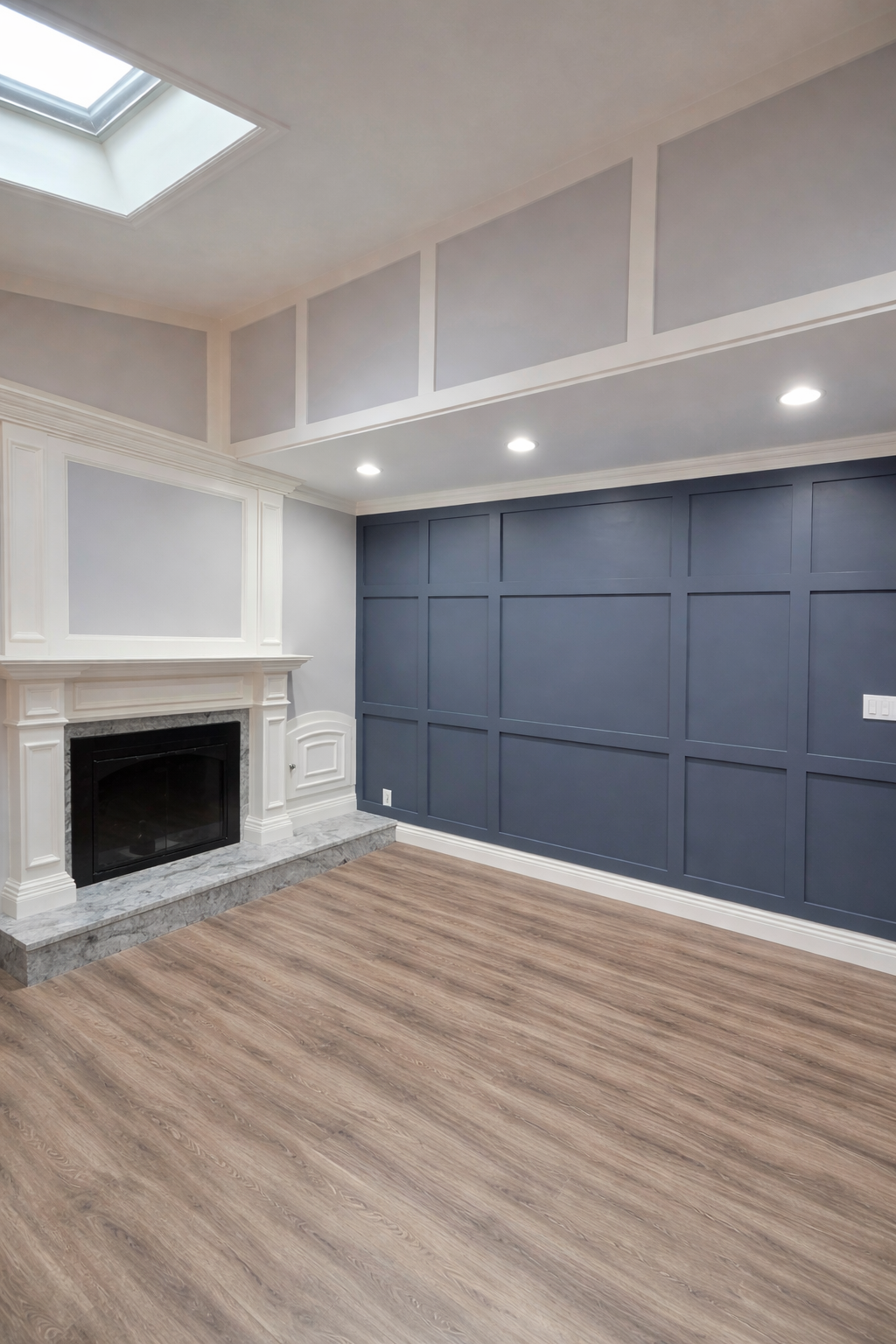 Empty living room with a white fireplace, blue accent wall with paneling, hardwood flooring, and a skylight in the ceiling.