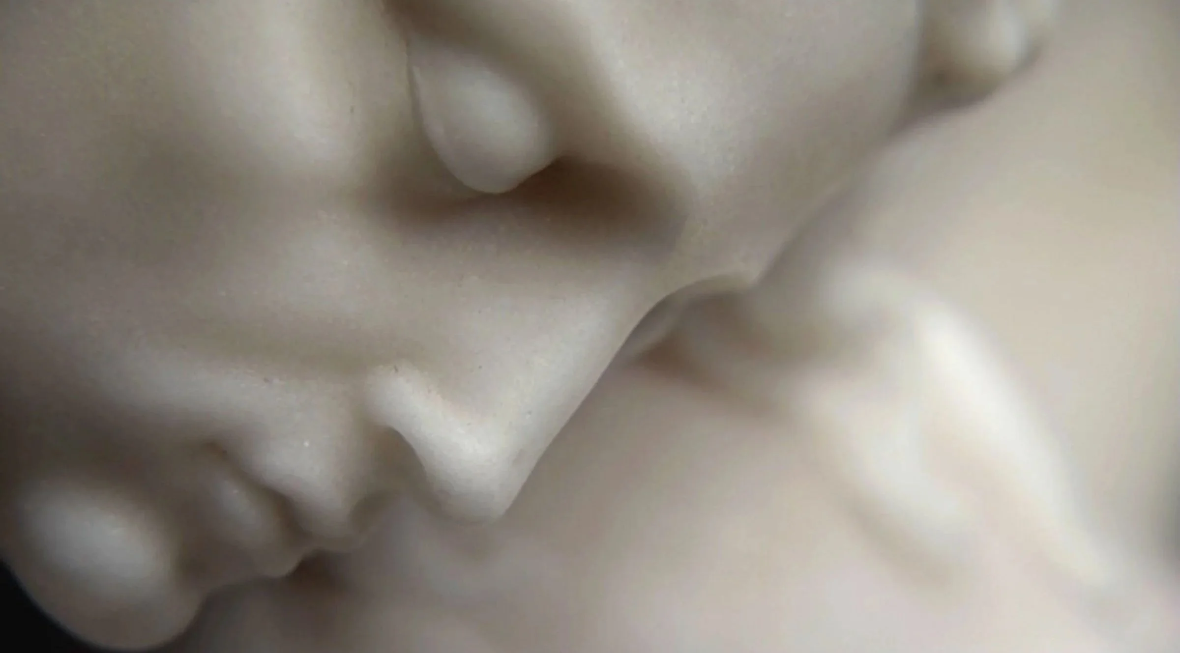 Close-up of a white marble sculpture's face, showing the nose and lips.