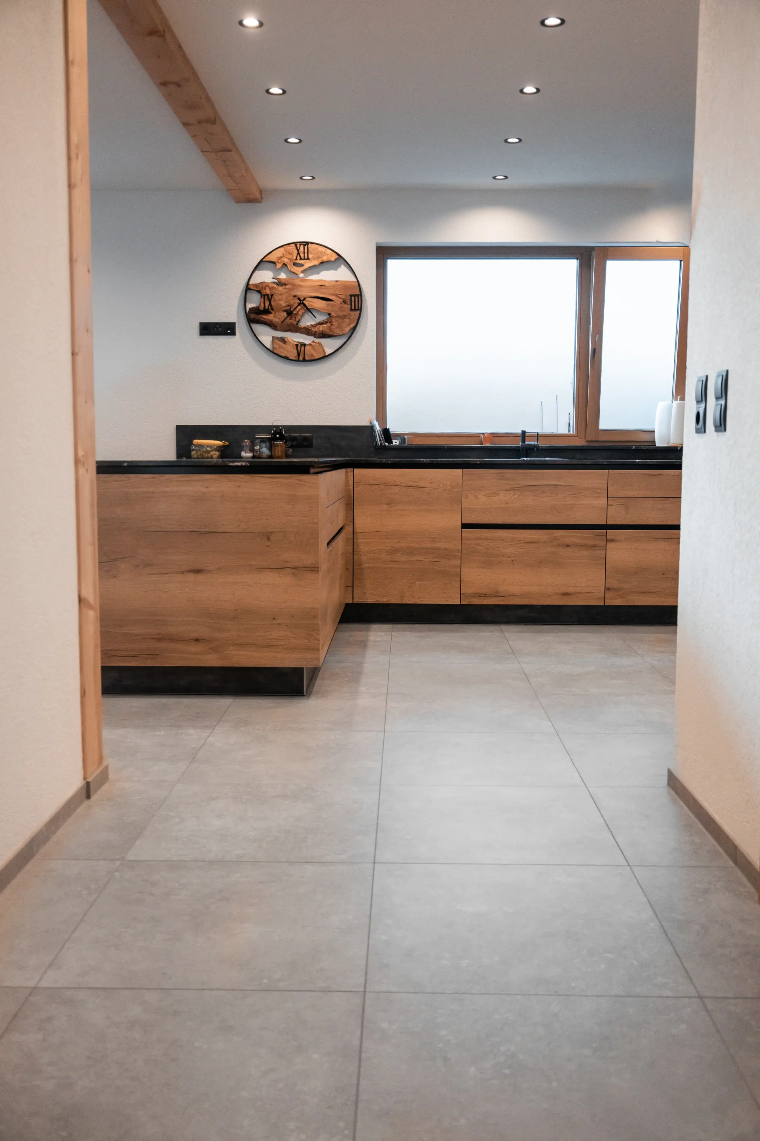 Moderne Küche mit Holzschränken, schwarzen Arbeitsflächen und einem Fenster