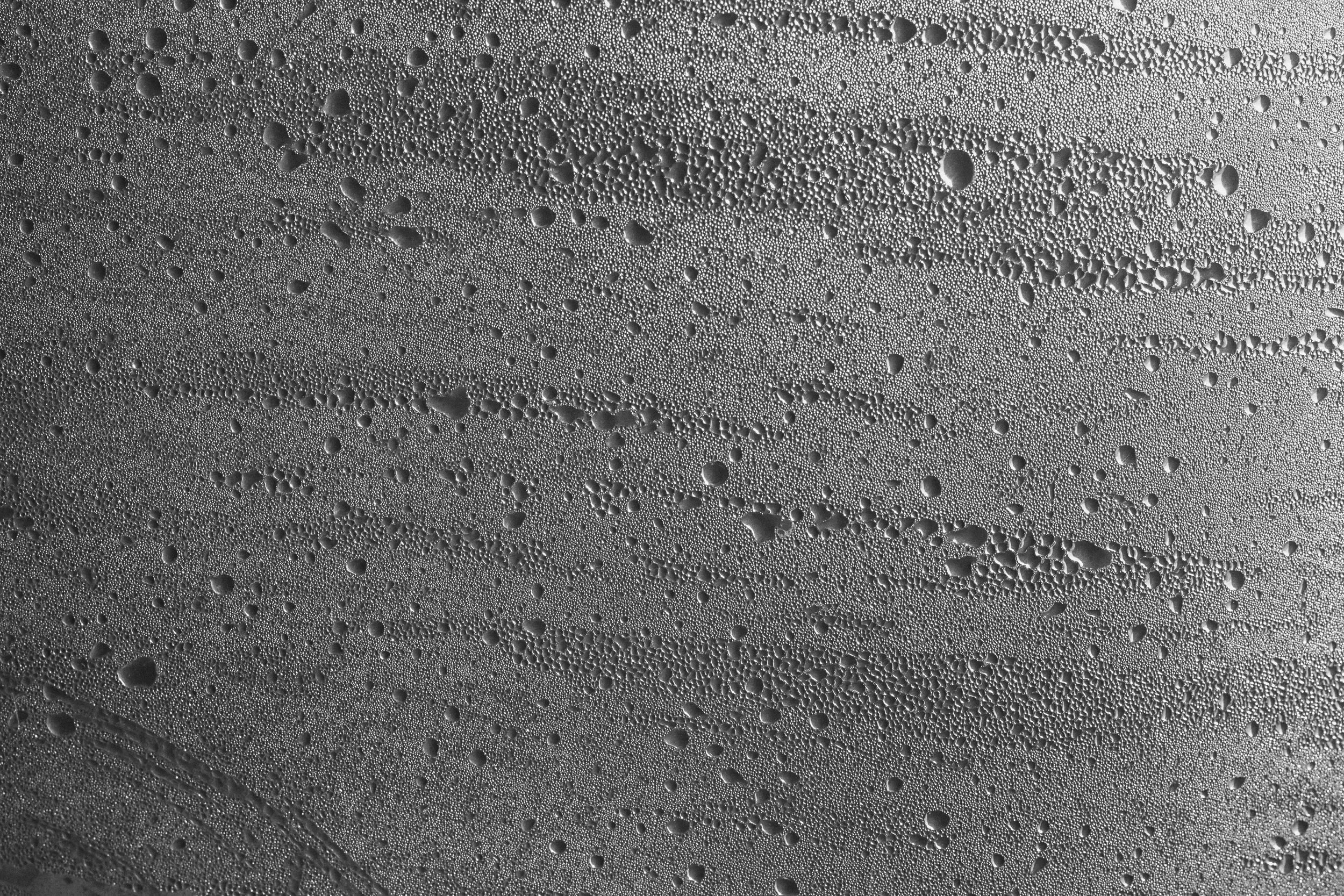 Close-up of water droplets on a smooth surface, creating a textured pattern with various sized droplets.