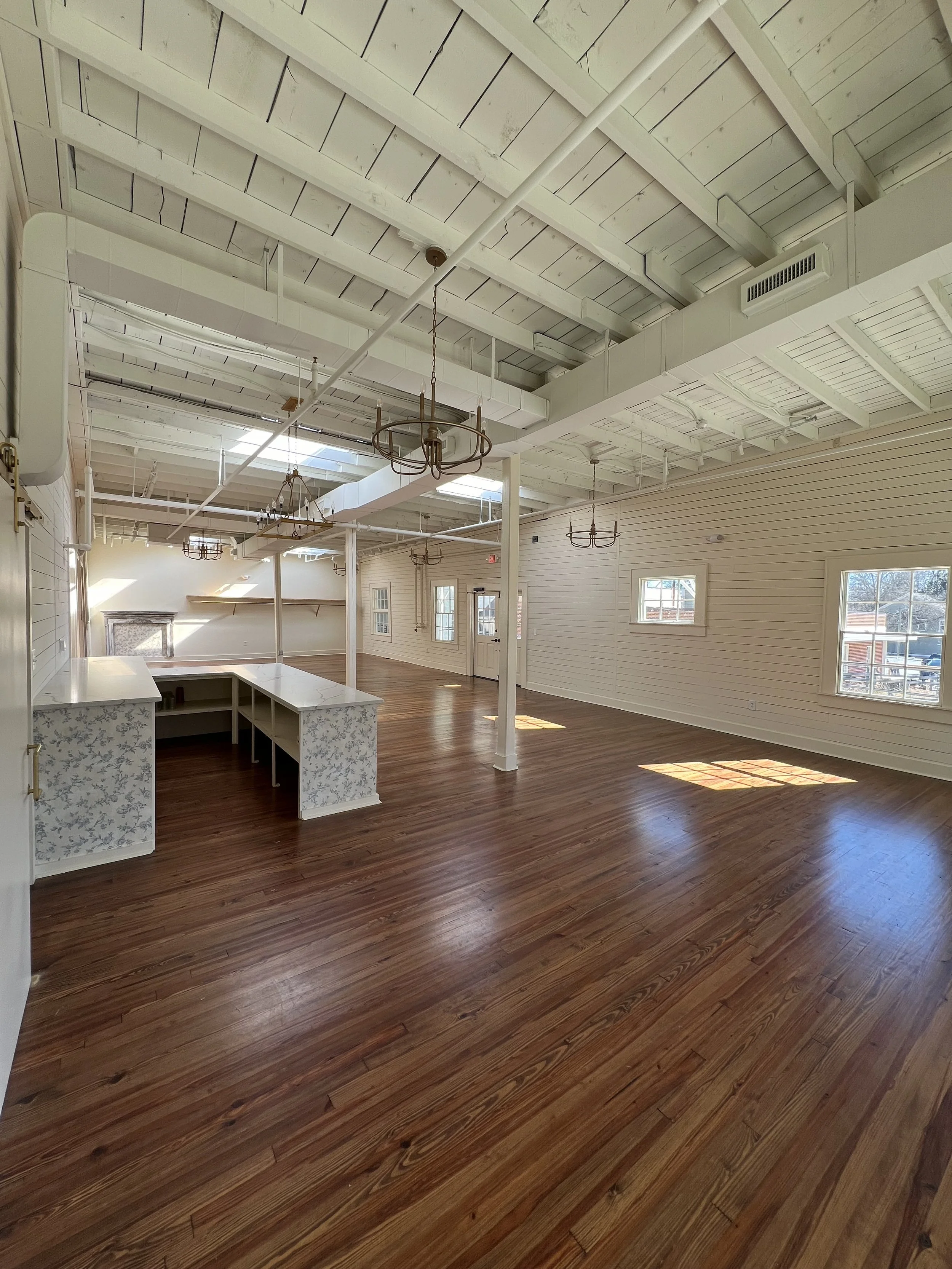 Bright, open layout of The Reverie event space in Winston-Salem with natural light and wood flooring.