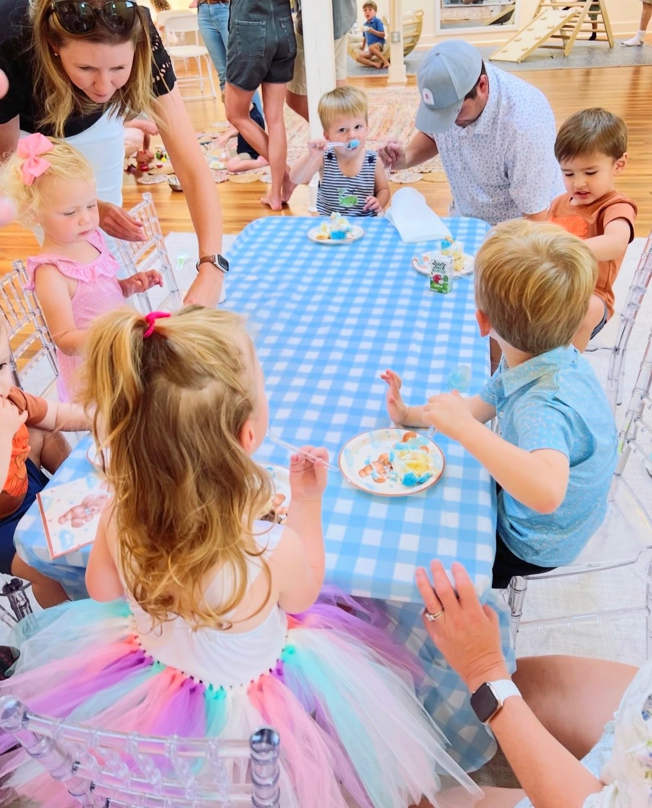 Moms and young children gathered around a table during a Mom League Winston-Salem playgroup, celebrating a special milestone with cake and community.
