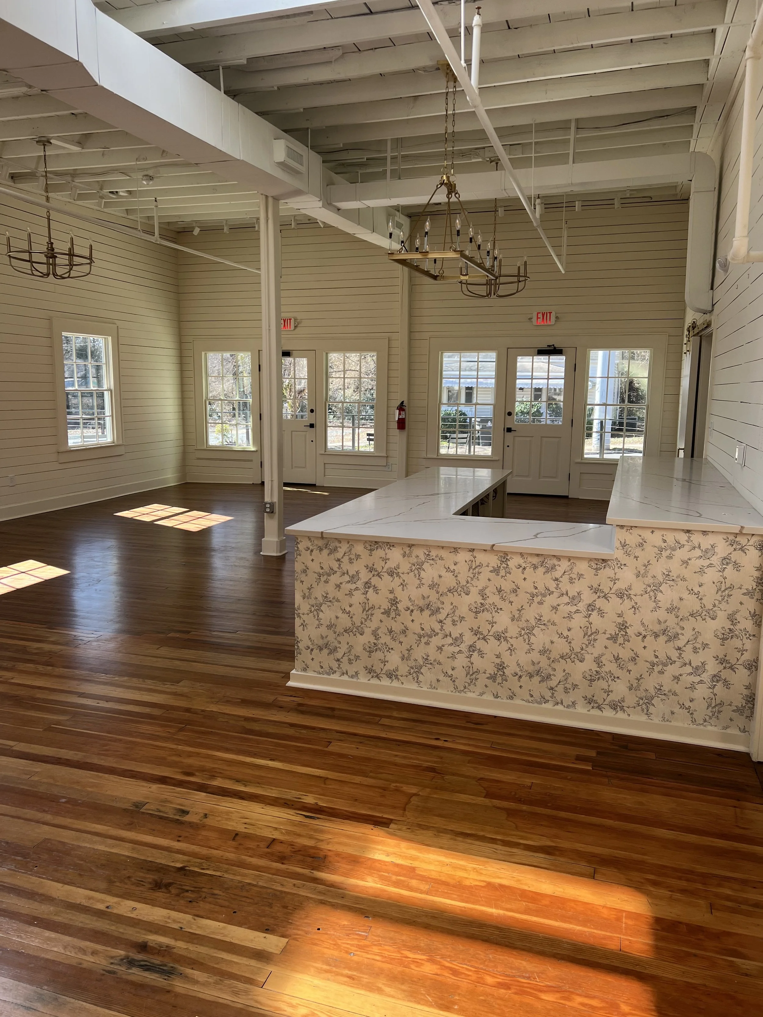 Interior of The Reverie in Winston-Salem with hardwood floors, white paneled walls, and chandeliers, home to Mom League events.