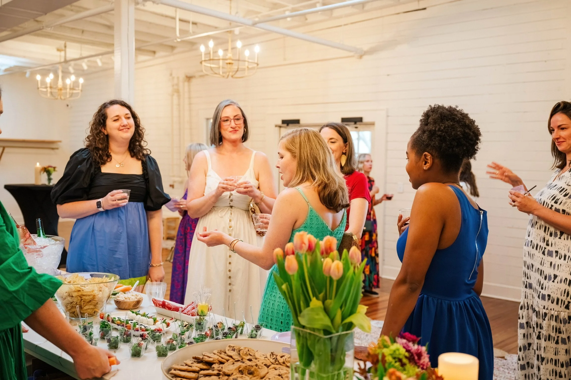 Group of moms chatting around a styled table during a Mom League playgroup gathering in Winston-Salem, NC.