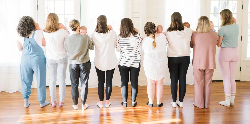A row of moms holding their babies at the window