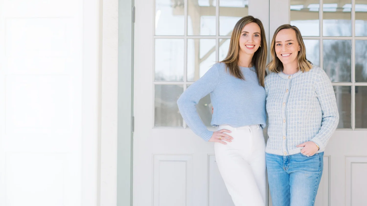 Kelly and Riley, the Mom League founders, standing in a bright doorway