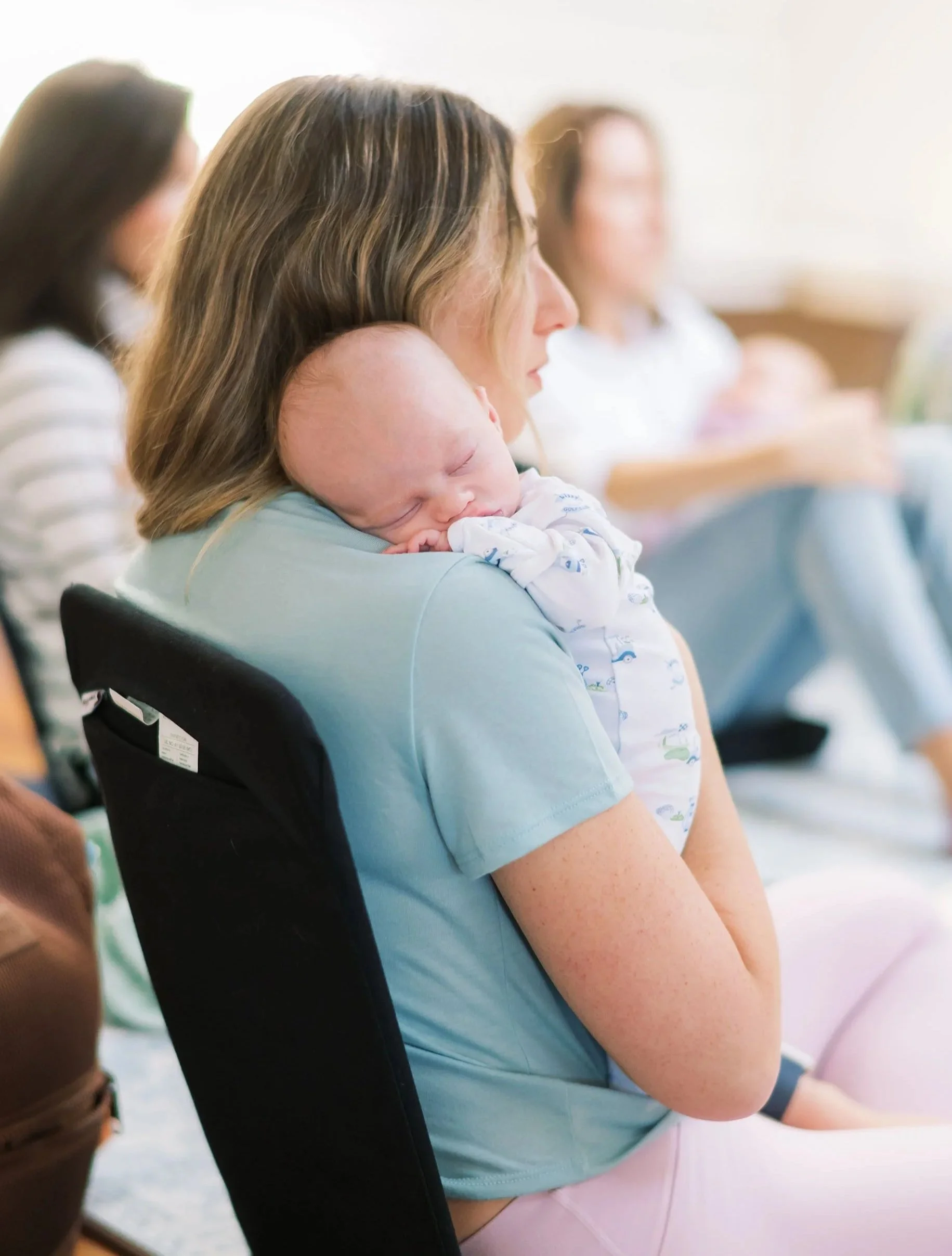 Mom holding her sleeping newborn during a Mom League Newborn Series class in Winston-Salem, NC.