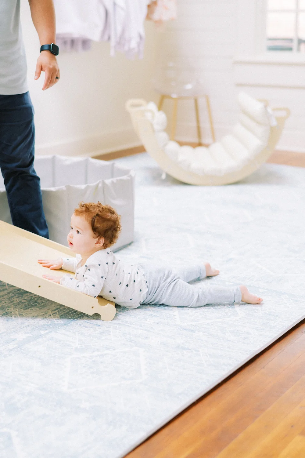 A baby on a small wooden slide in the bright play space