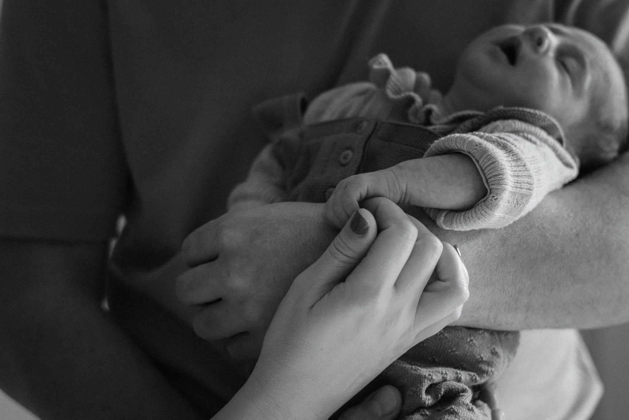 Un bébé souriant étant tenu par une personne adulte.