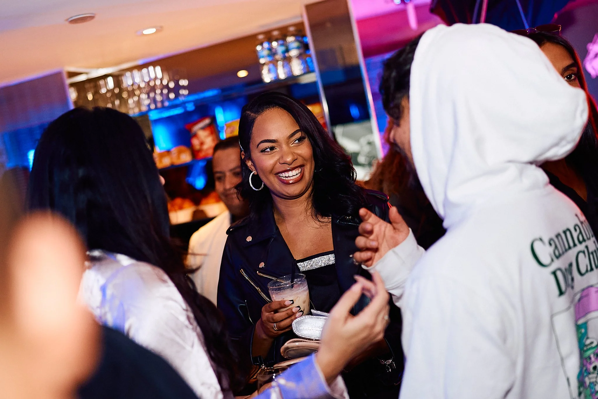 Grupo de personas conversando en un ambiente de bar o restaurante con iluminación de neón