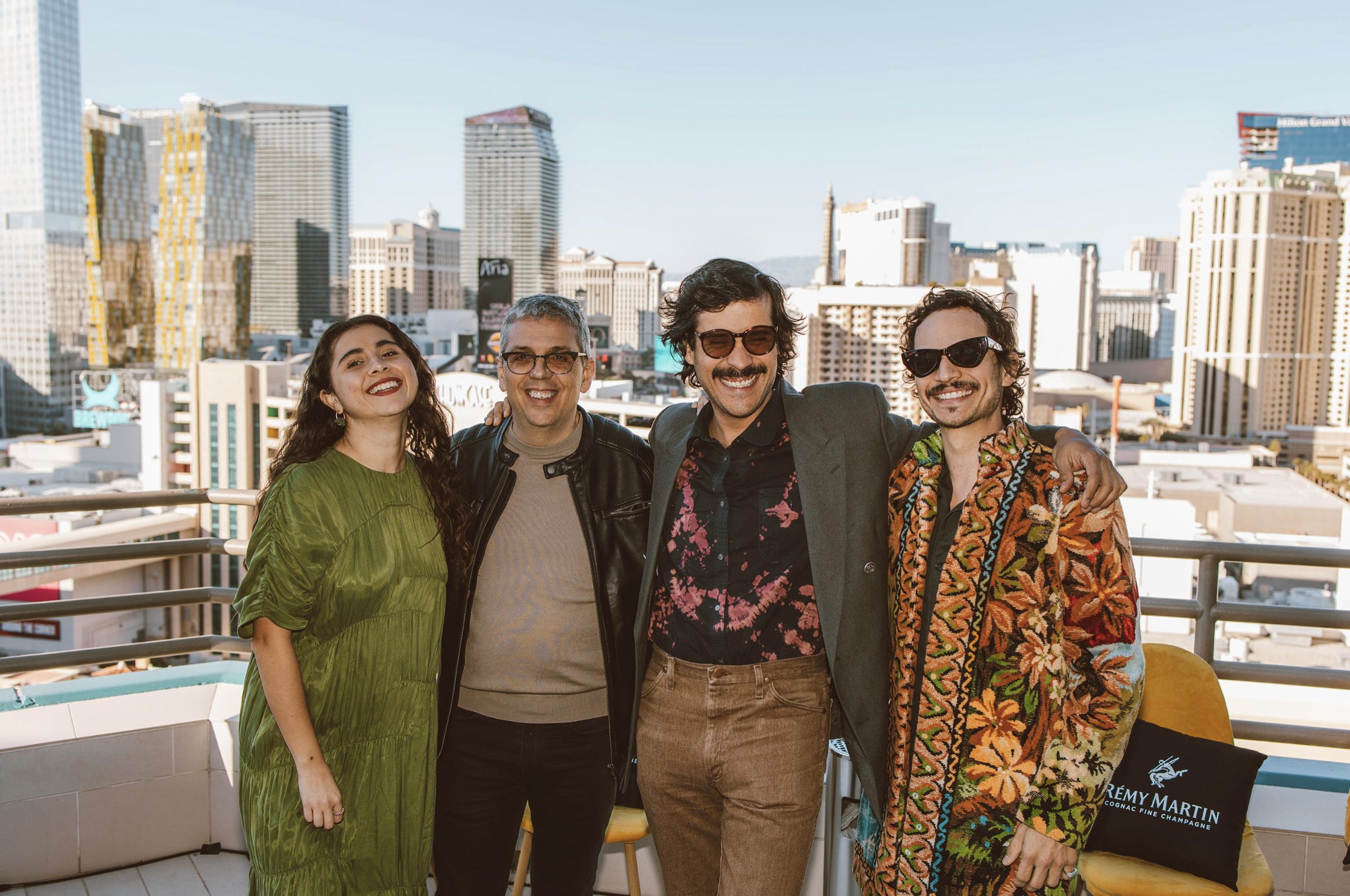 Cinco personas sonriendo y posando juntas en una terraza con vista a la ciudad de Las Vegas en el fondo.