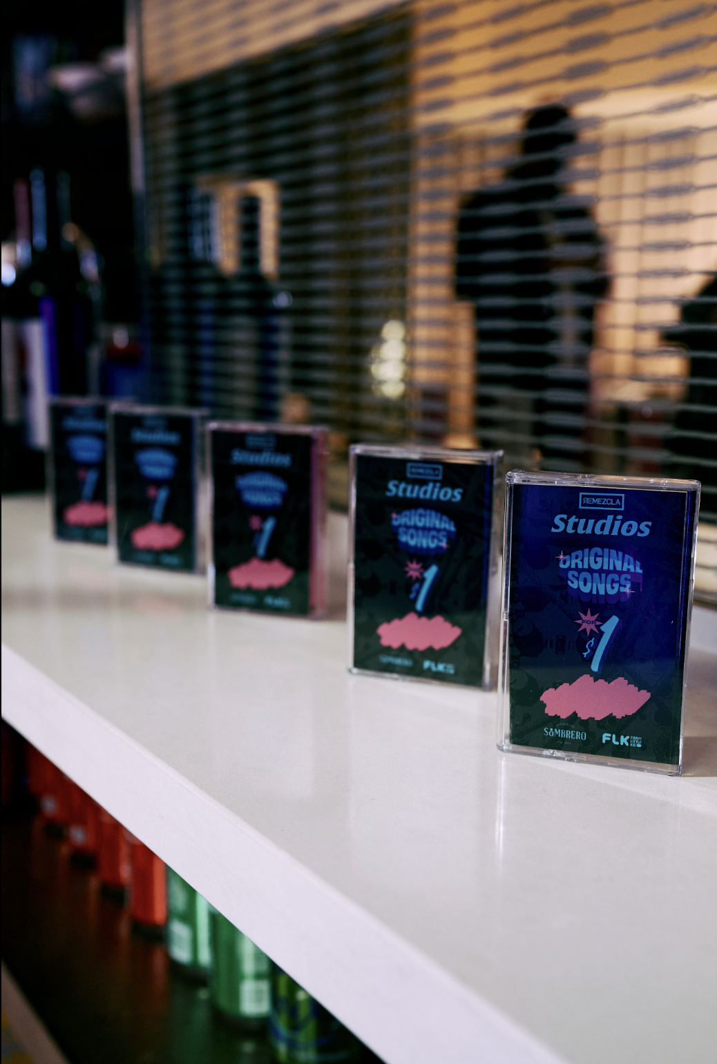 Cuatro discos compactos en una mesa blanca, con una pared de ladrillos y una ventana con persianas metálicas en el fondo.