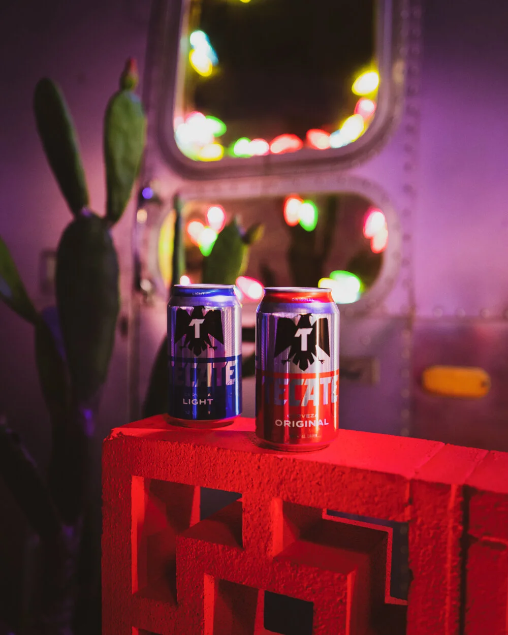 Latas de bebidas en una mesa roja con luces de colores borrosas en el fondo