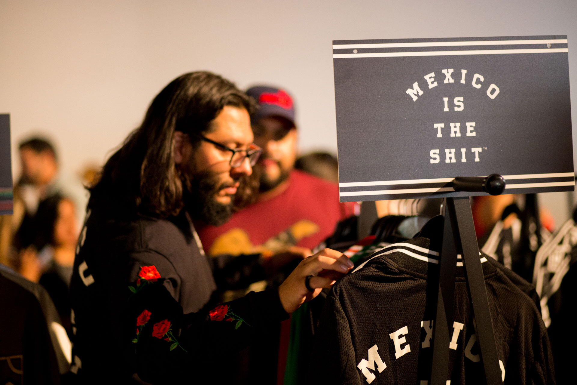 Persona en una tienda mira ropa con cartel que dice "México es una mierda".
