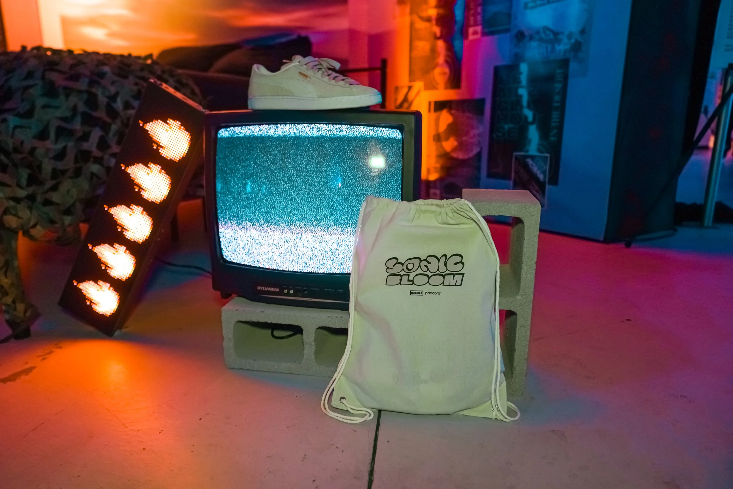 Arte retro con televisión antigua, camiseta, y zapatos hecho con objetos vintage y luces de colores en un ambiente en tonos cálidos y fríos.