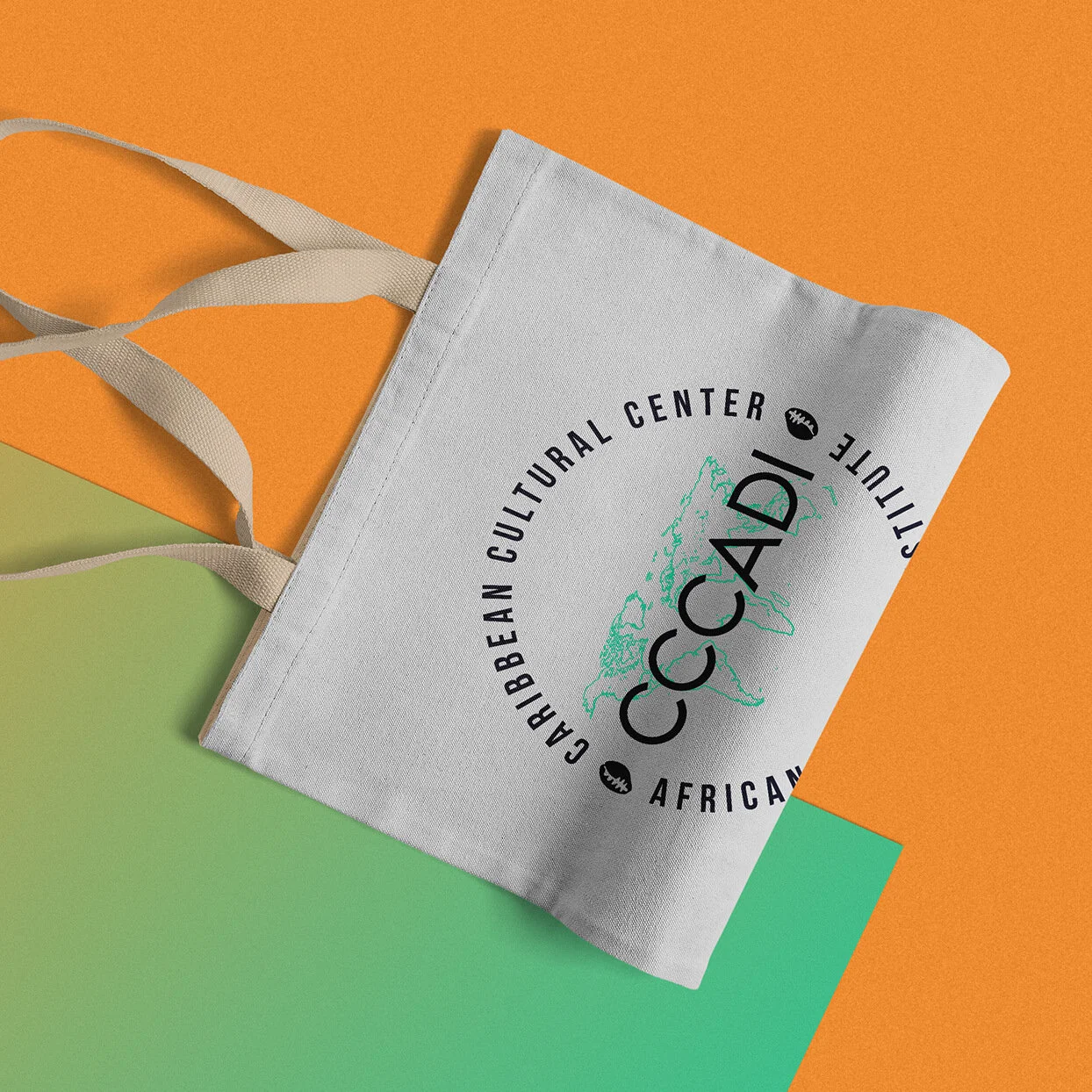 Bolsa de tela blanca con el logo del Caribbean Cultural Center establecido en Costa Rica o en el Caribe, sobre fondo de colores naranja y verde