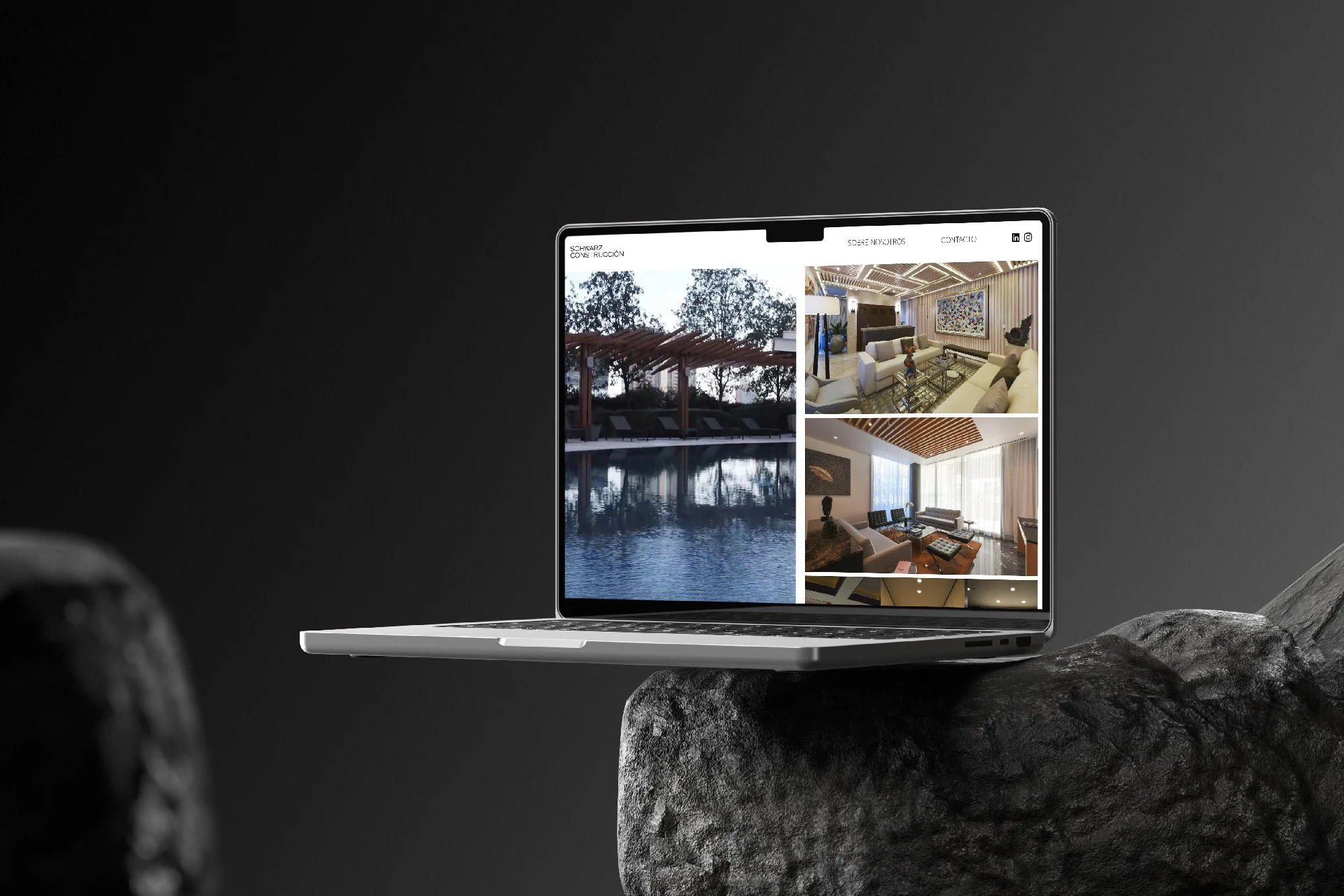 Portátil en una piedra mostrando una página web con imágenes de casas u hoteles de lujo, incluyendo piscinas y salas de estar elegantes.