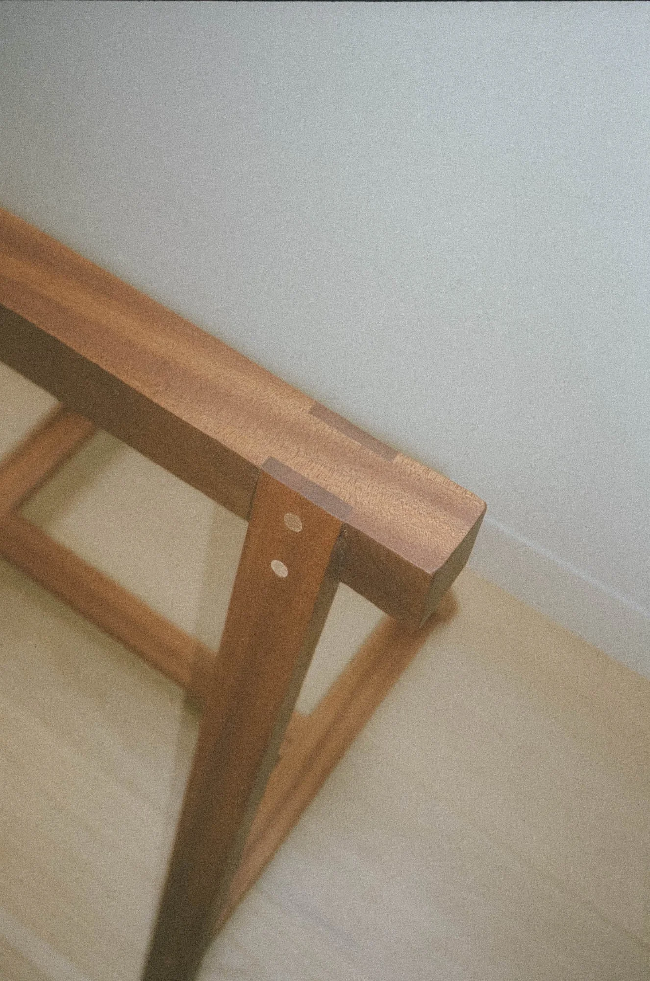 Close-up of a wooden sawhorse frame against a light-colored wall and floor.