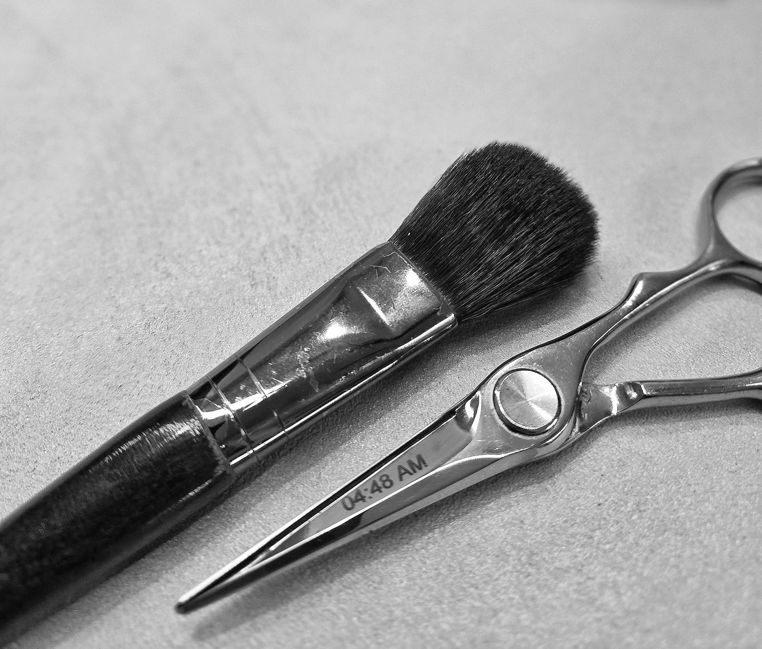 Pennello da trucco e forbici con manico metallico e lama curva, entrambi in acciaio