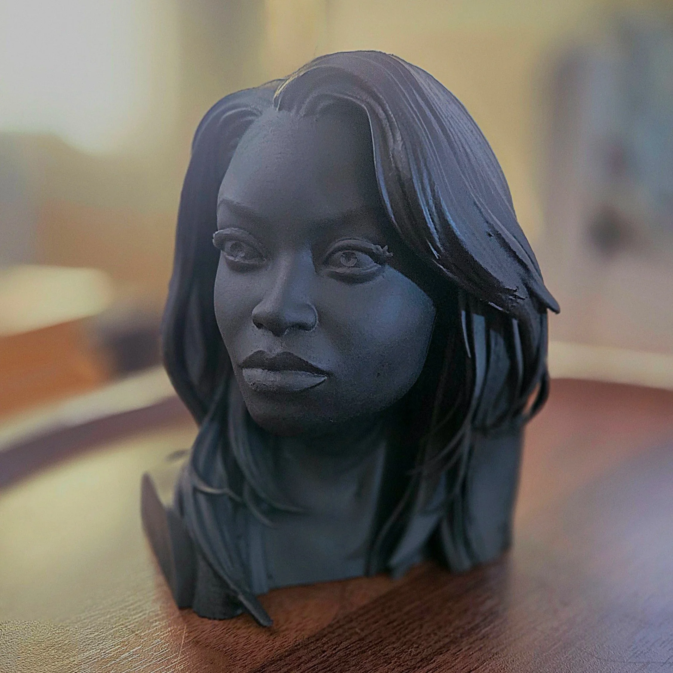 A matte black sculpted bust of a Nike Onile with long straight hair.