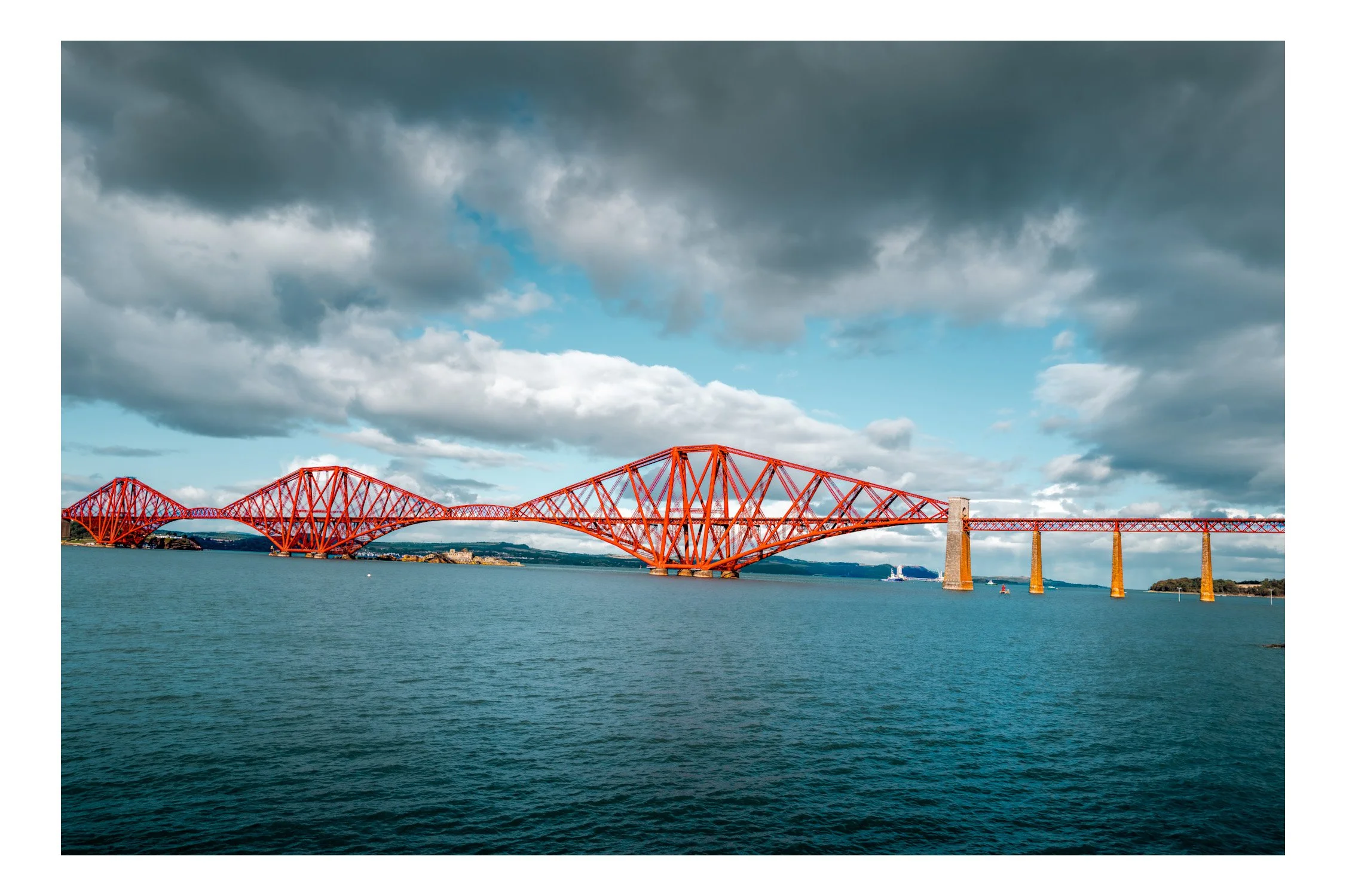 The Forth Bridge, a red cantilever railway bridge over the Firth of Forth in Scotland, with a partly cloudy sky and water below.