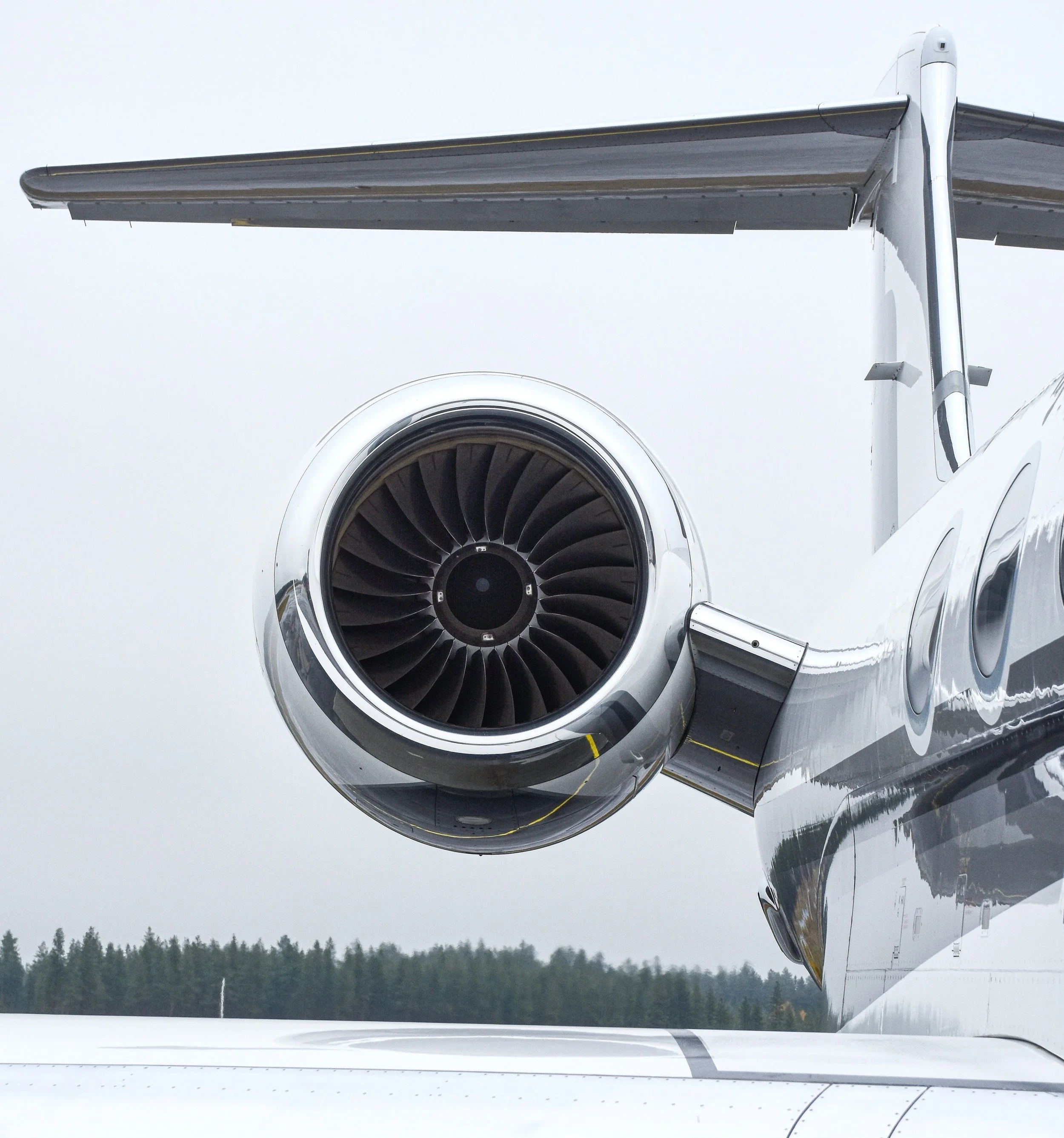 Close-up of a private jet's jet engine and wing on a cloudy day.