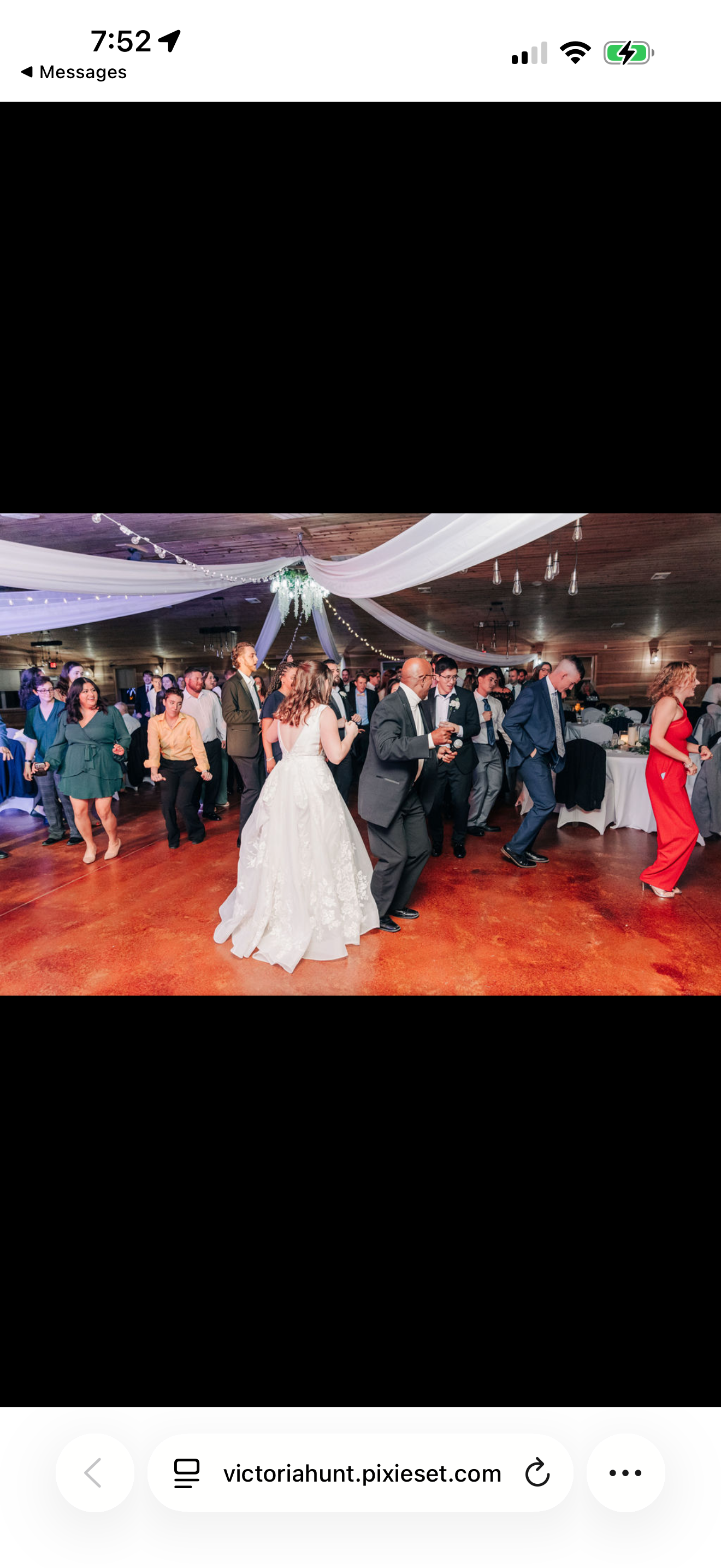 People dancing at a wedding reception with decorations on the ceiling and round tables in the background.