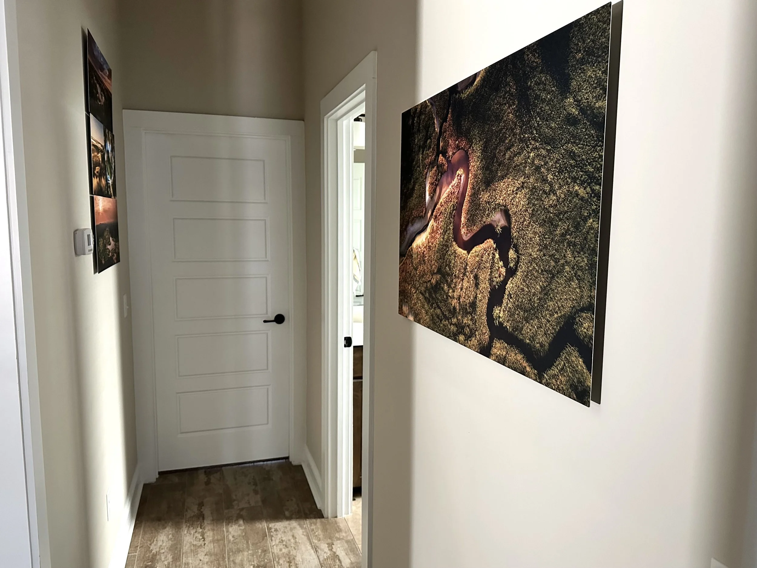 Large fine art metal print with modern float mount displayed in a residential hallway, photographed by Derek Bradley Photography.