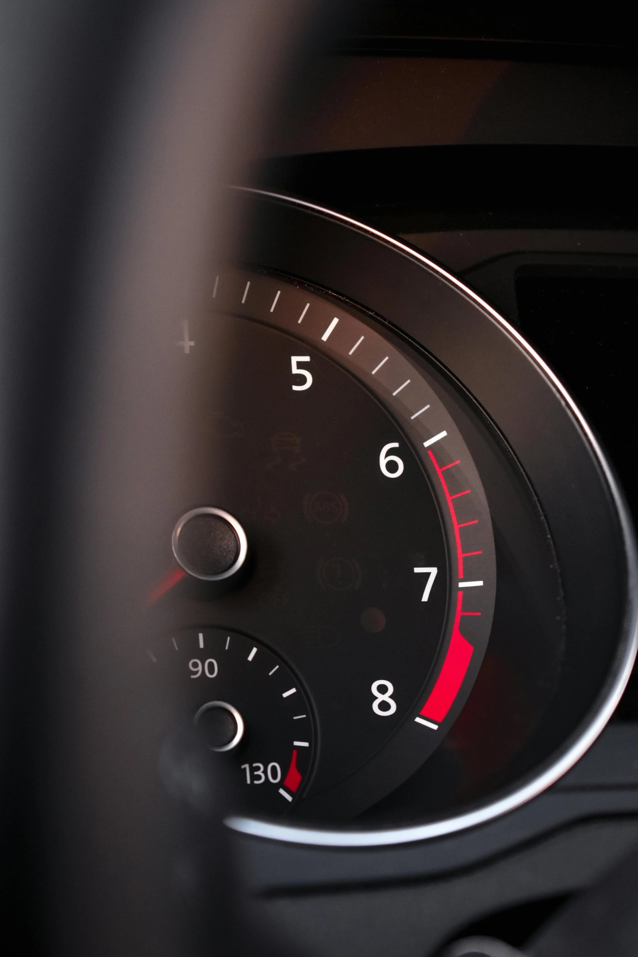 Close-up of a car's tachometer and temperature gauge, with the tachometer needle pointing to 2.5 and the temperature gauge indicating around 130 degrees Fahrenheit.