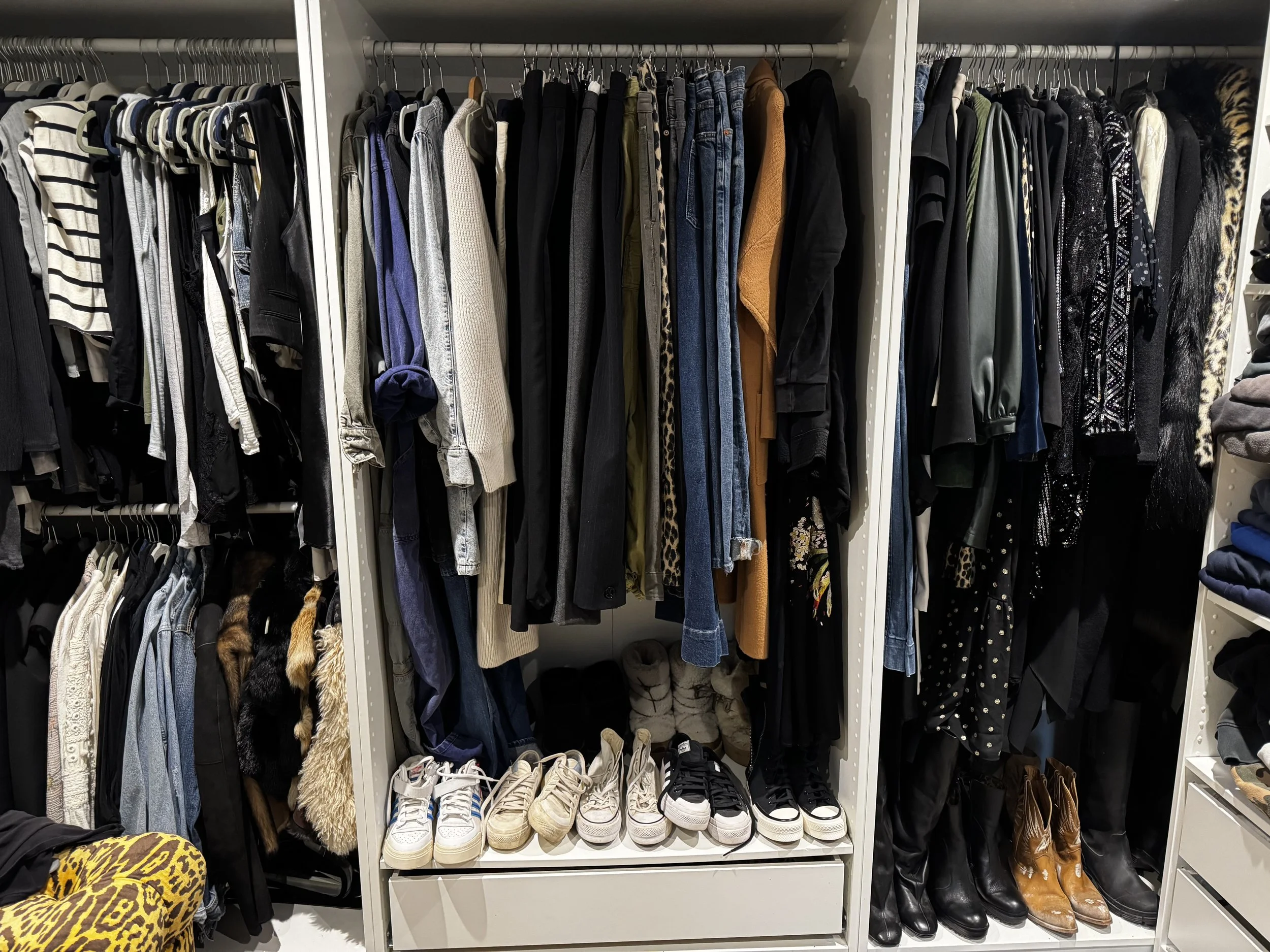 Closet with hanging clothes, shoes on the floor, and folded items on shelves