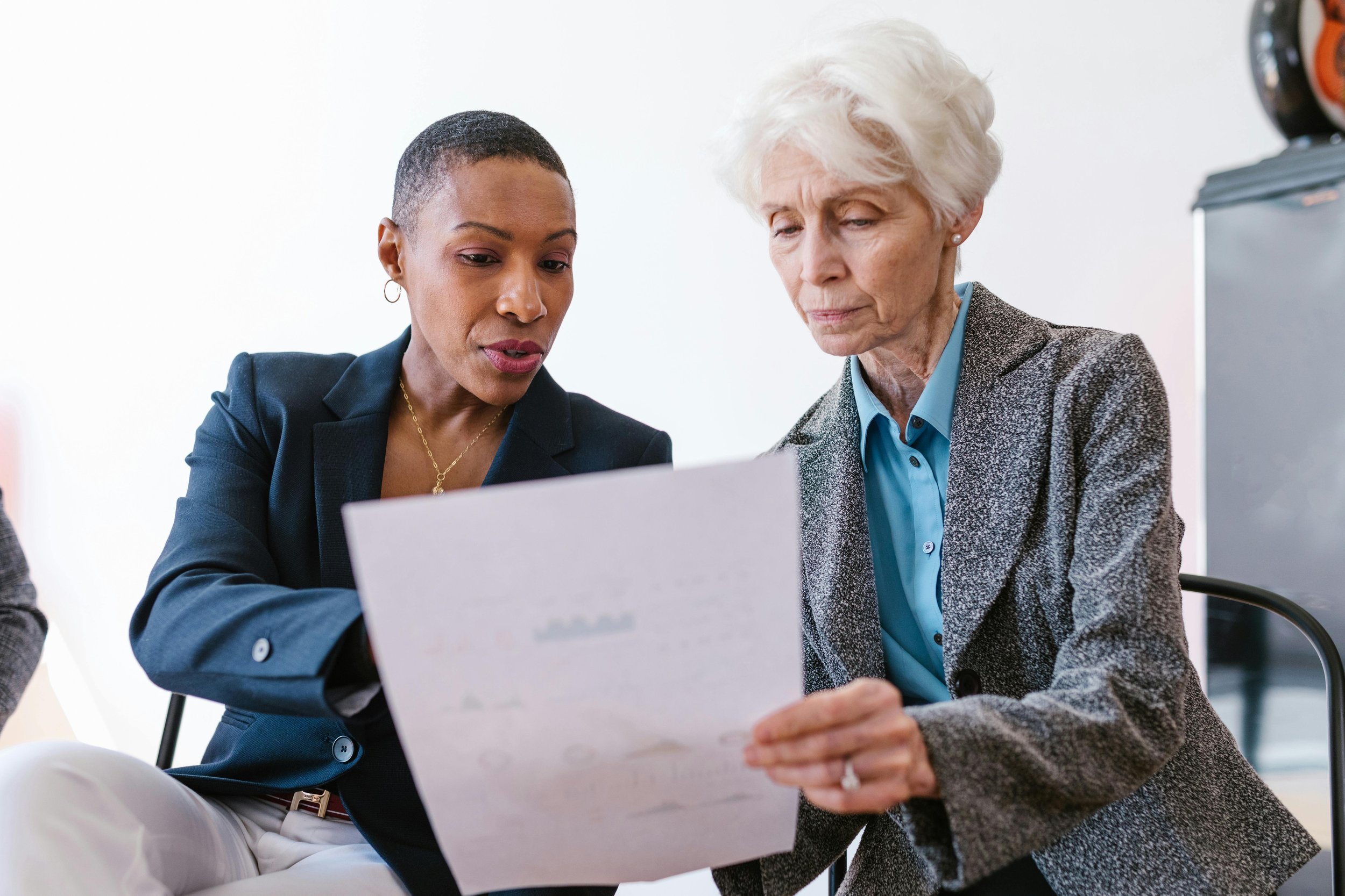 Two women looking at a document together in an office setting.