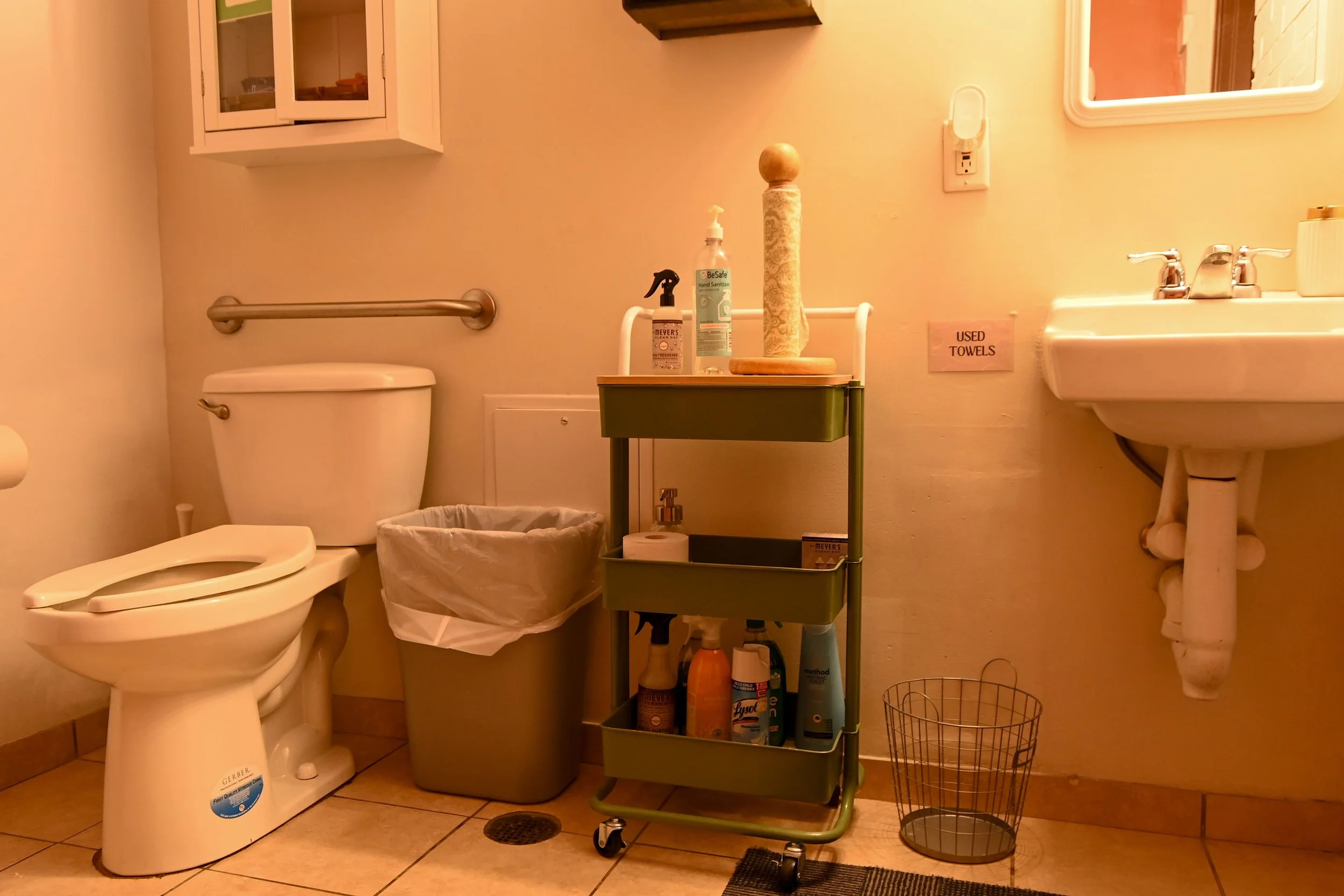 RESTROOM: Better view of toilet, sink, and hand towels and towel bin, as well as an open trash can.