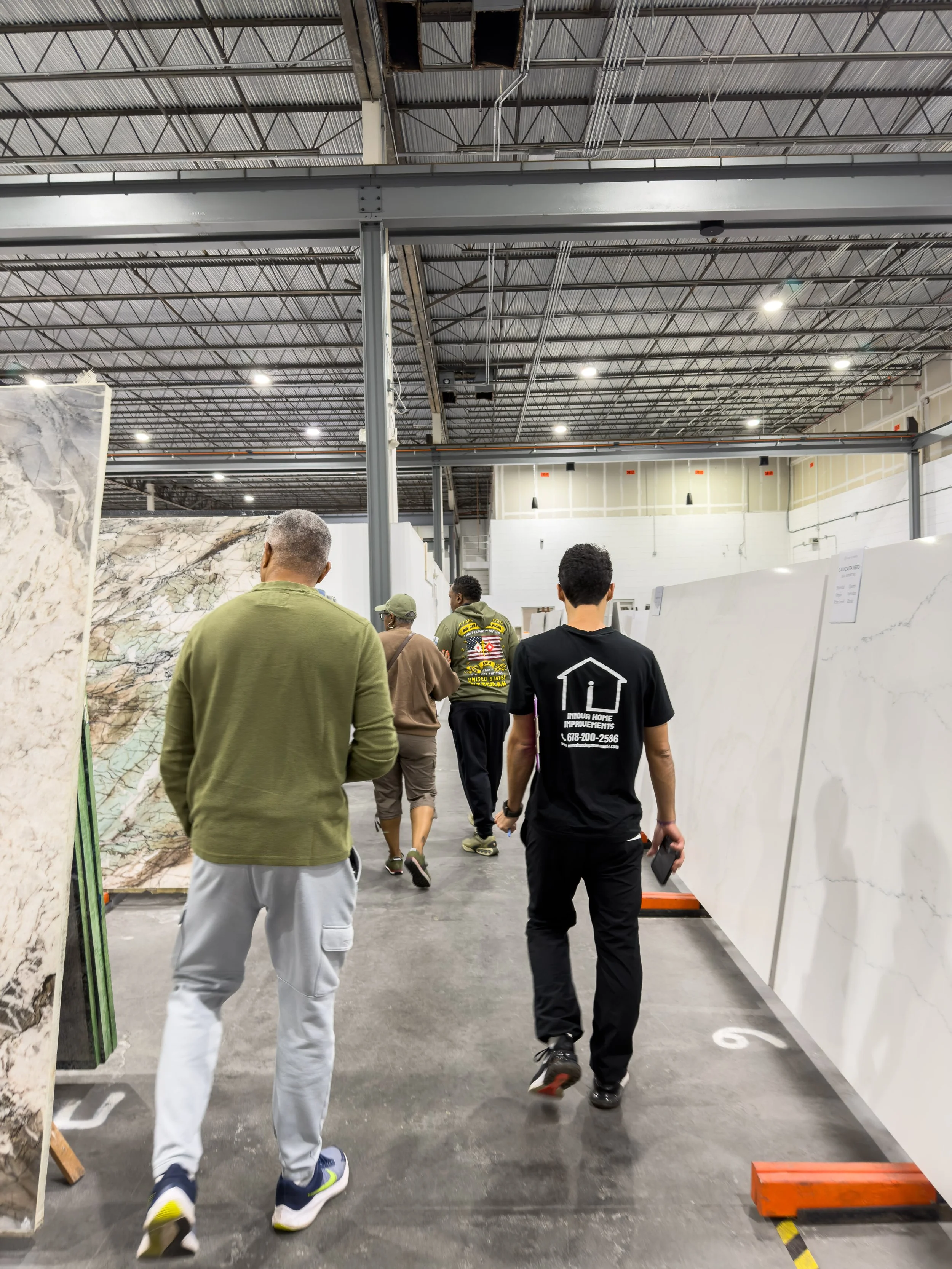 People shopping for large slabs of marble or granite in a warehouse or warehouse store.