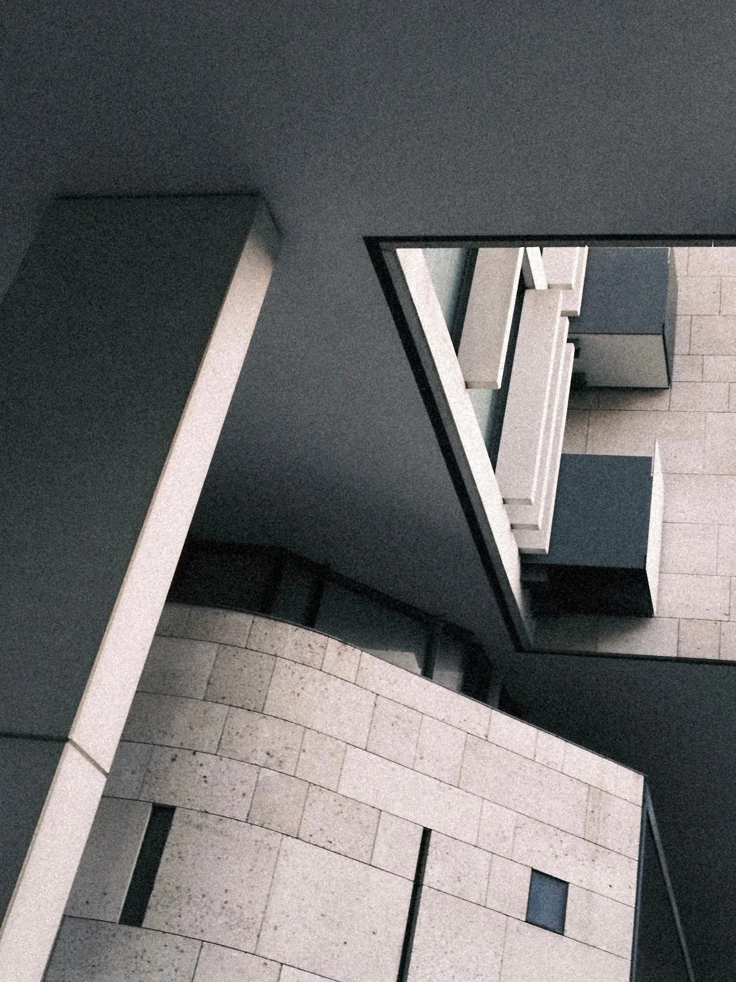 Abstract architectural view of a modern building with geometric shapes, gray walls, and glass windows, taken from below.