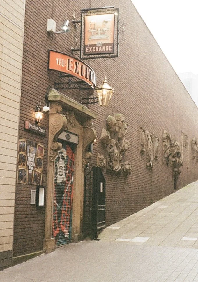 Brick building with a sign reading "The Exchange" and decorative bust sculptures on the wall.