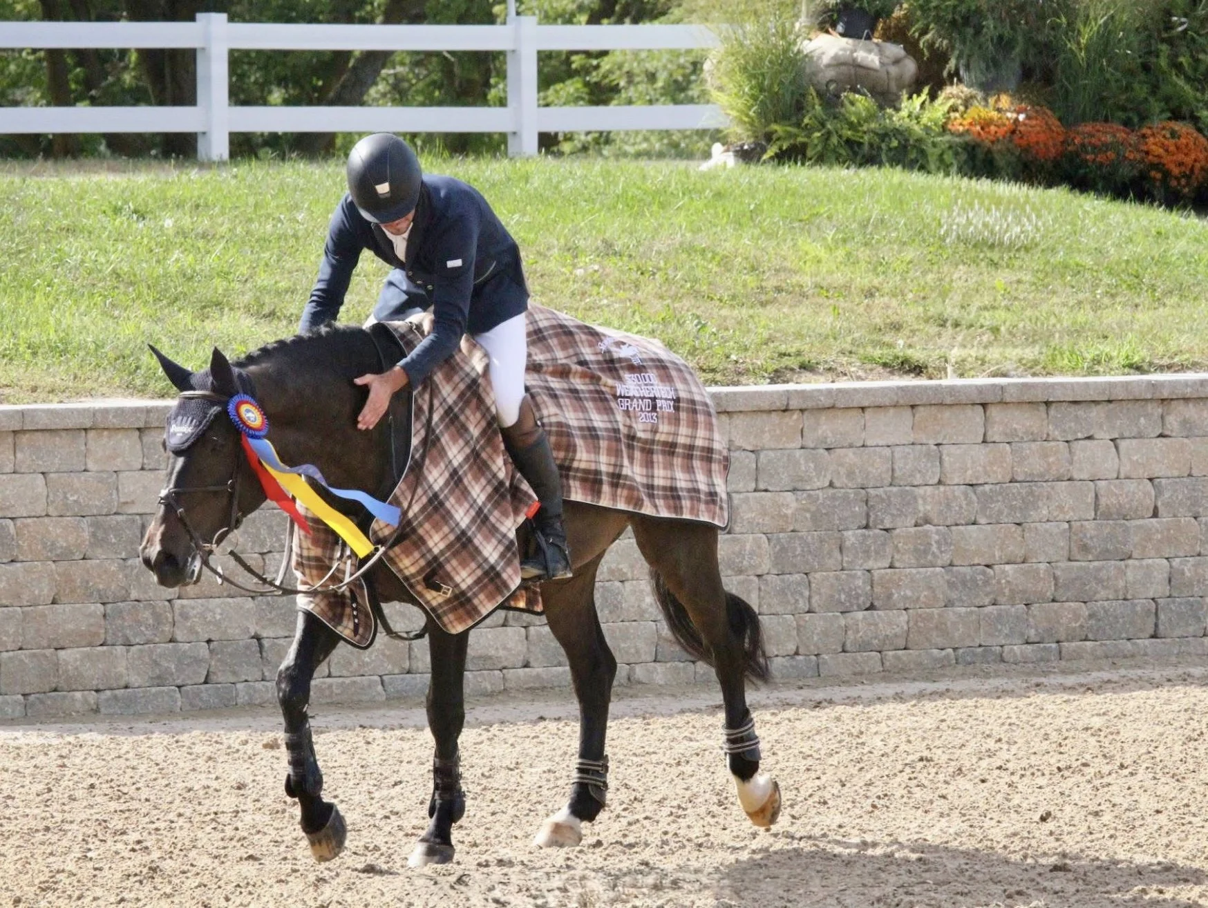 Ryan Genn patting his horse with a championship ribbon at GS Equestrian