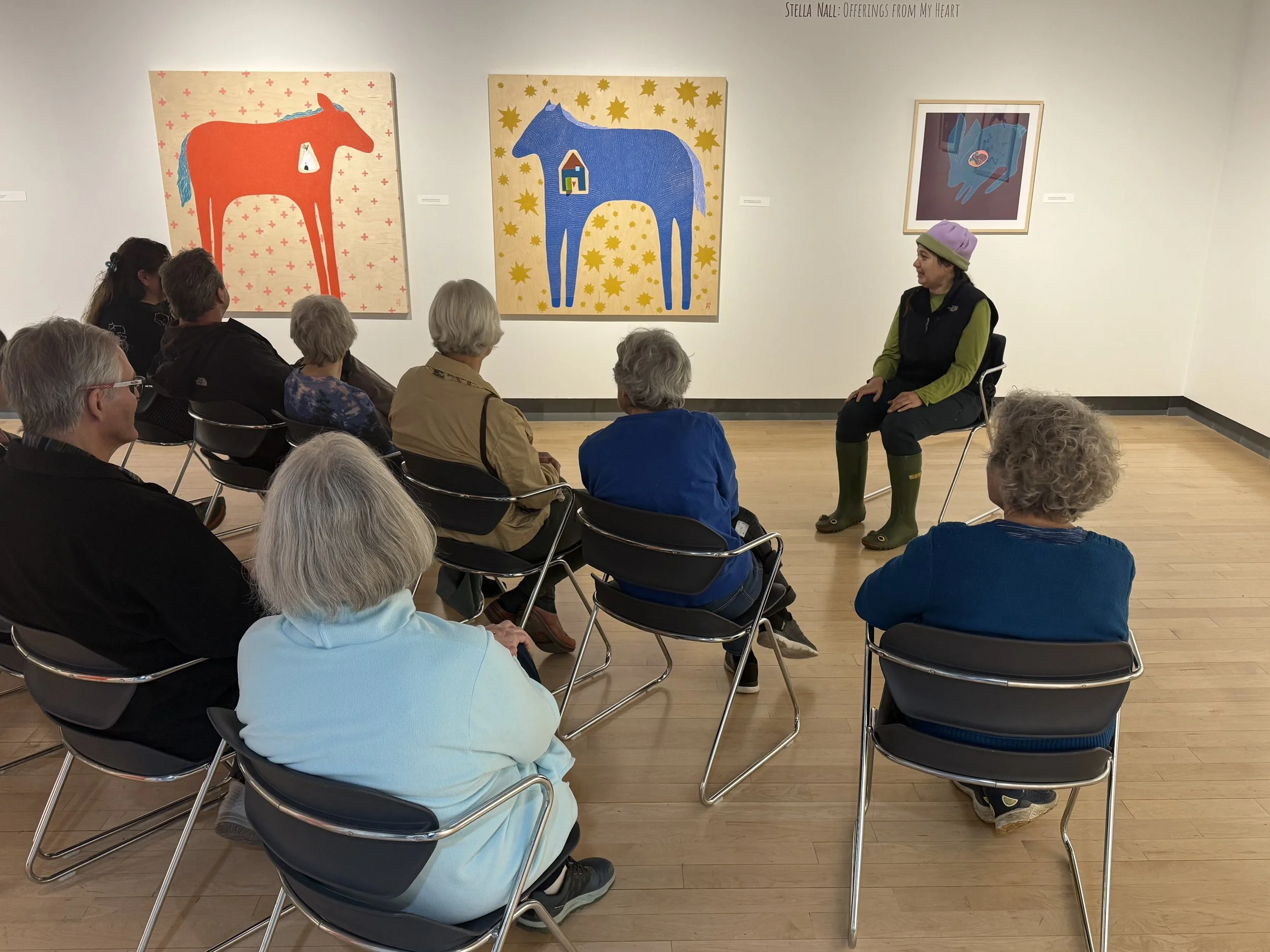 A group sits in a circle around exhibiting artists, Stella Nall, during an Art in the Moment session. 