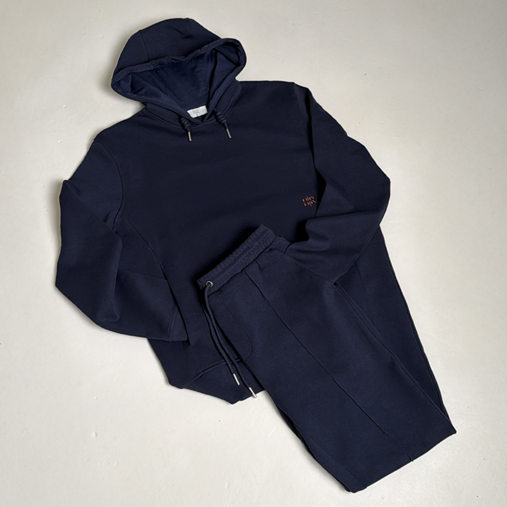Navy blue hoodie and matching sweatpants laid out on a light-colored surface.