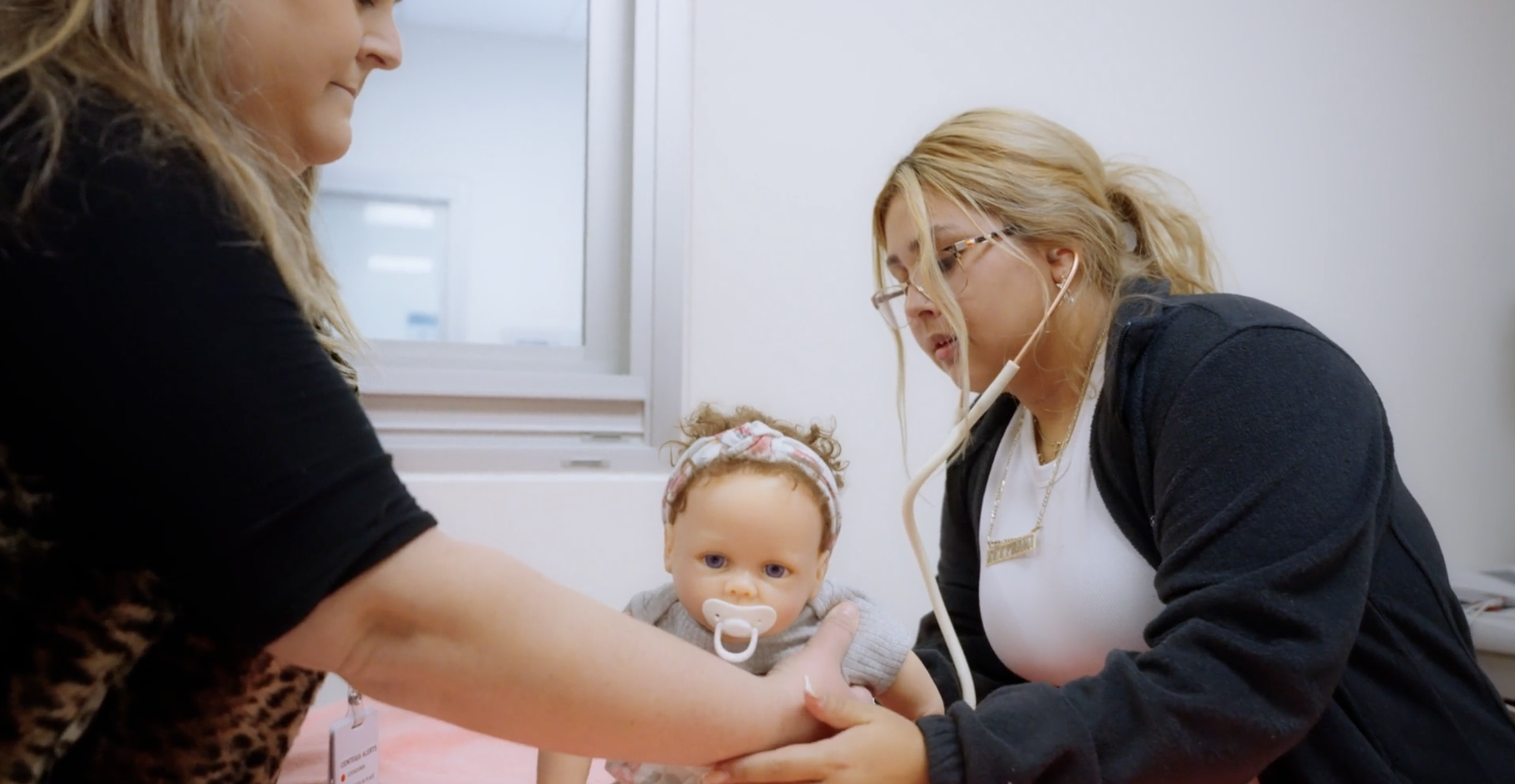 Medical professionals examining a young girl with a pacifier in her mouth, in a clinical setting.