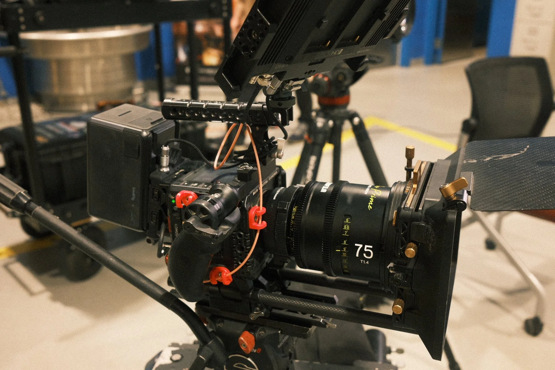 A professional cinema camera setup with a large lens, matte box, monitor, and various accessories in a studio setting.