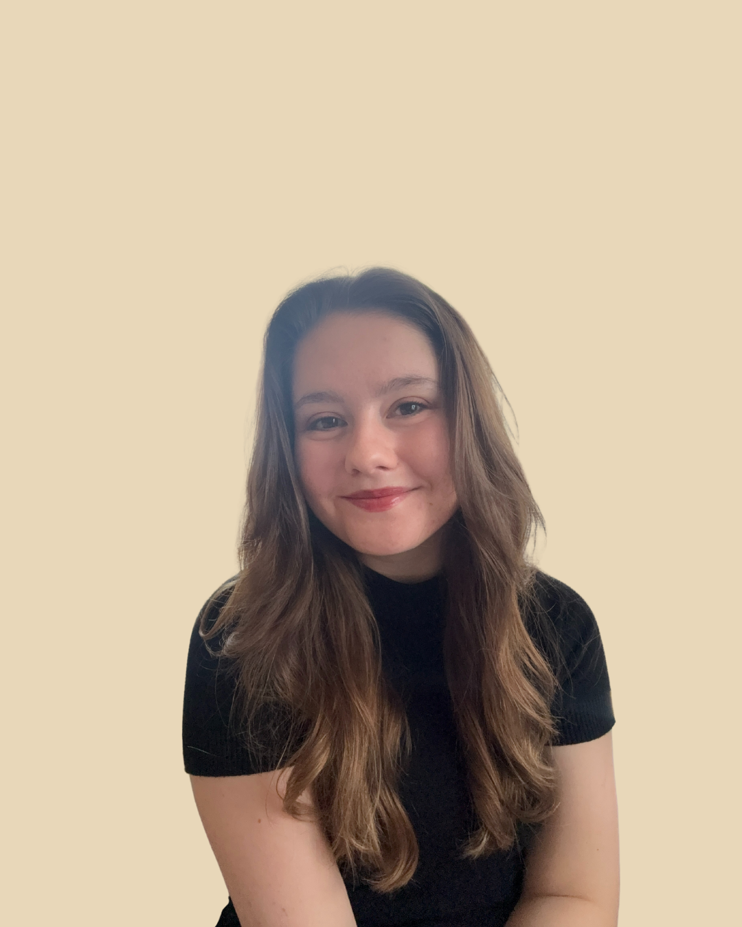 A young woman with long wavy brown hair wearing a black shirt, smiling softly, against a plain beige background.