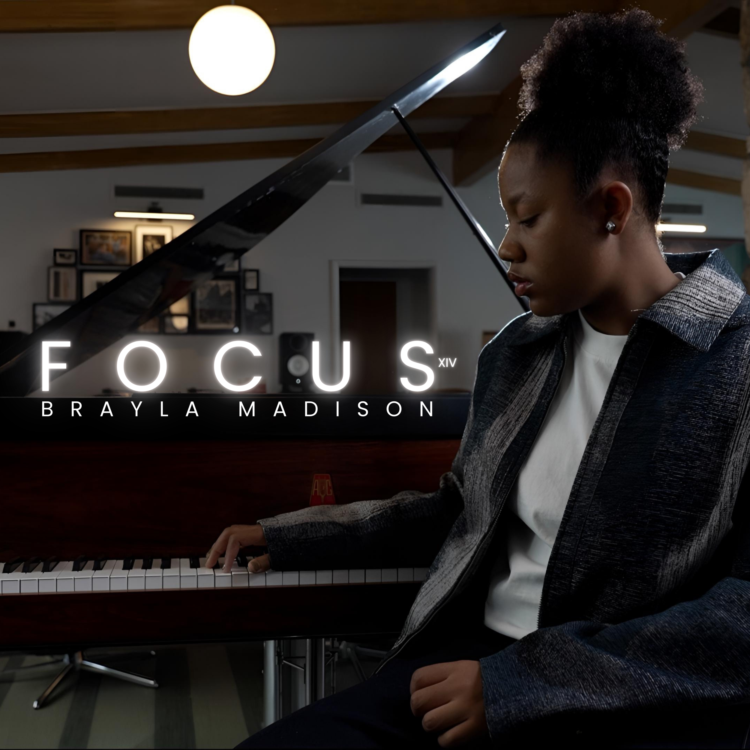 A woman sitting at a grand piano, wearing a gray blazer and a white shirt, with a focused expression, in a room with framed pictures on the wall and a large round light fixture above.