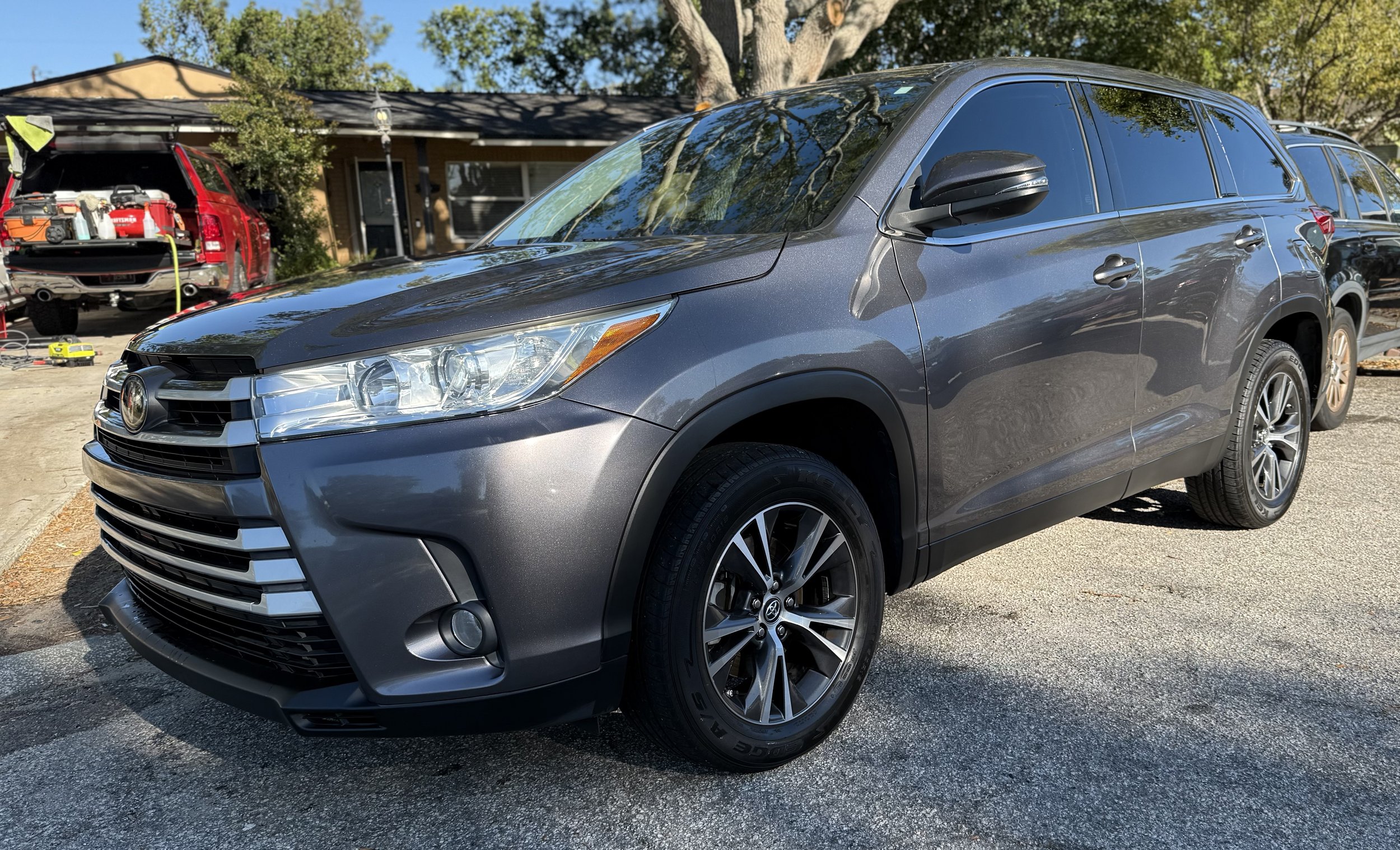 Grey Toyota RAV4 parked on the street with trees and houses in the background.