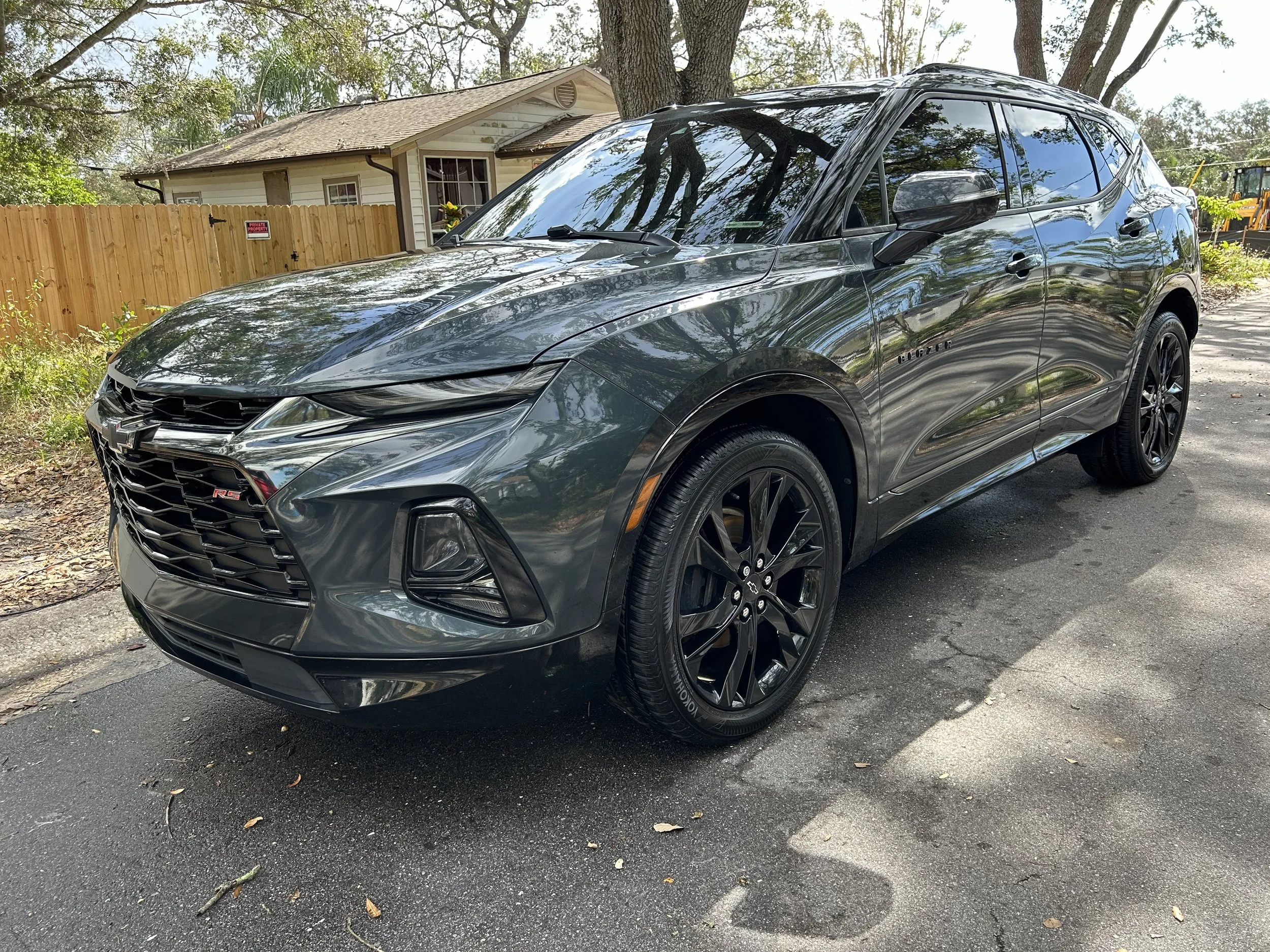 Grey Chevrolet SUV parked on driveway with house and trees in background.