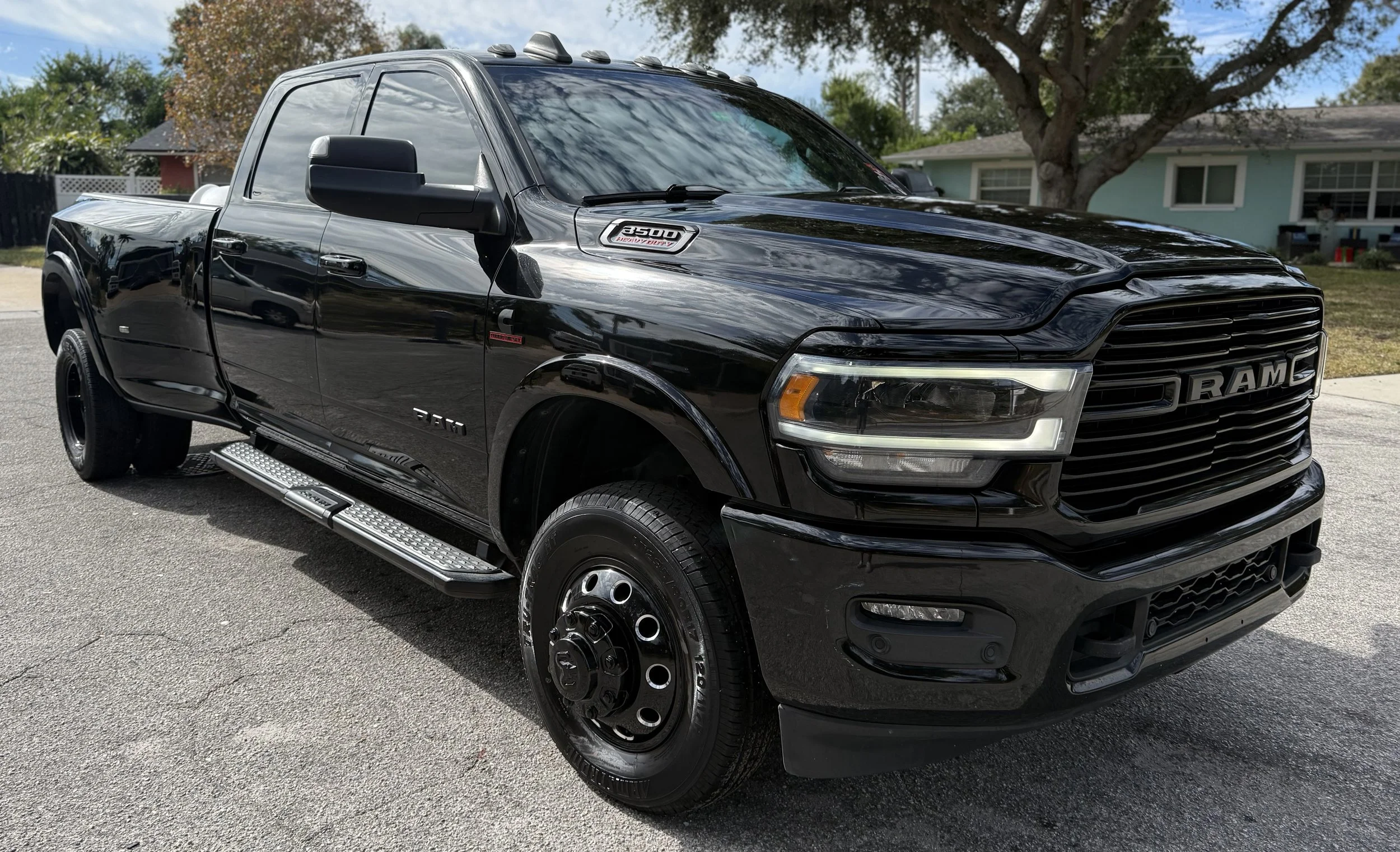A black RAM pickup truck parked on a residential street with trees and houses in the background.